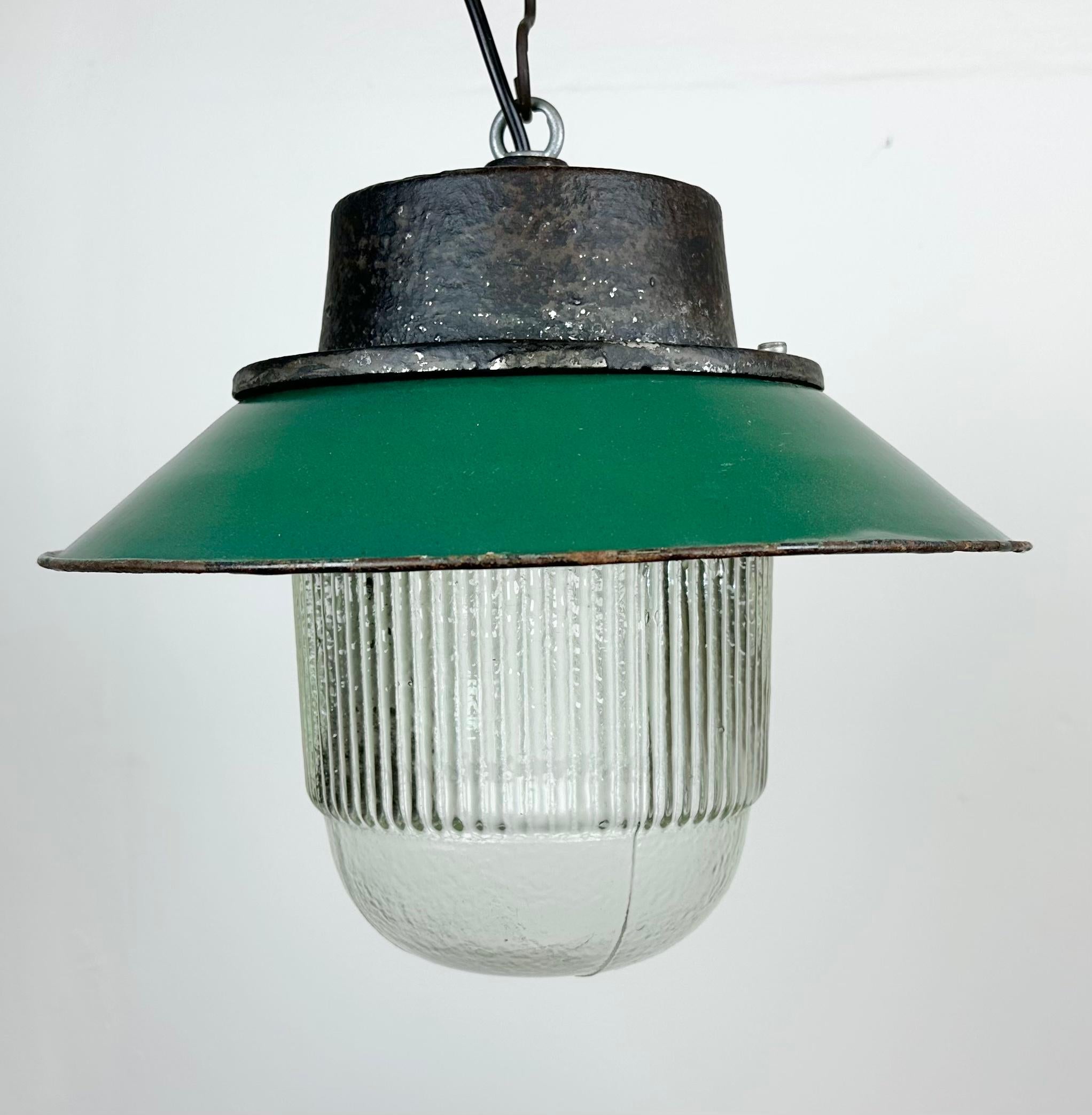 Industrial hanging lamp manufactured in Poland during the 1960s. It features a green enamel shade with a white enamel interior, a grey cast iron top, and a striped glass cover. The porcelain socket requires E 27/ E26 lightbulbs. New wire. The weight