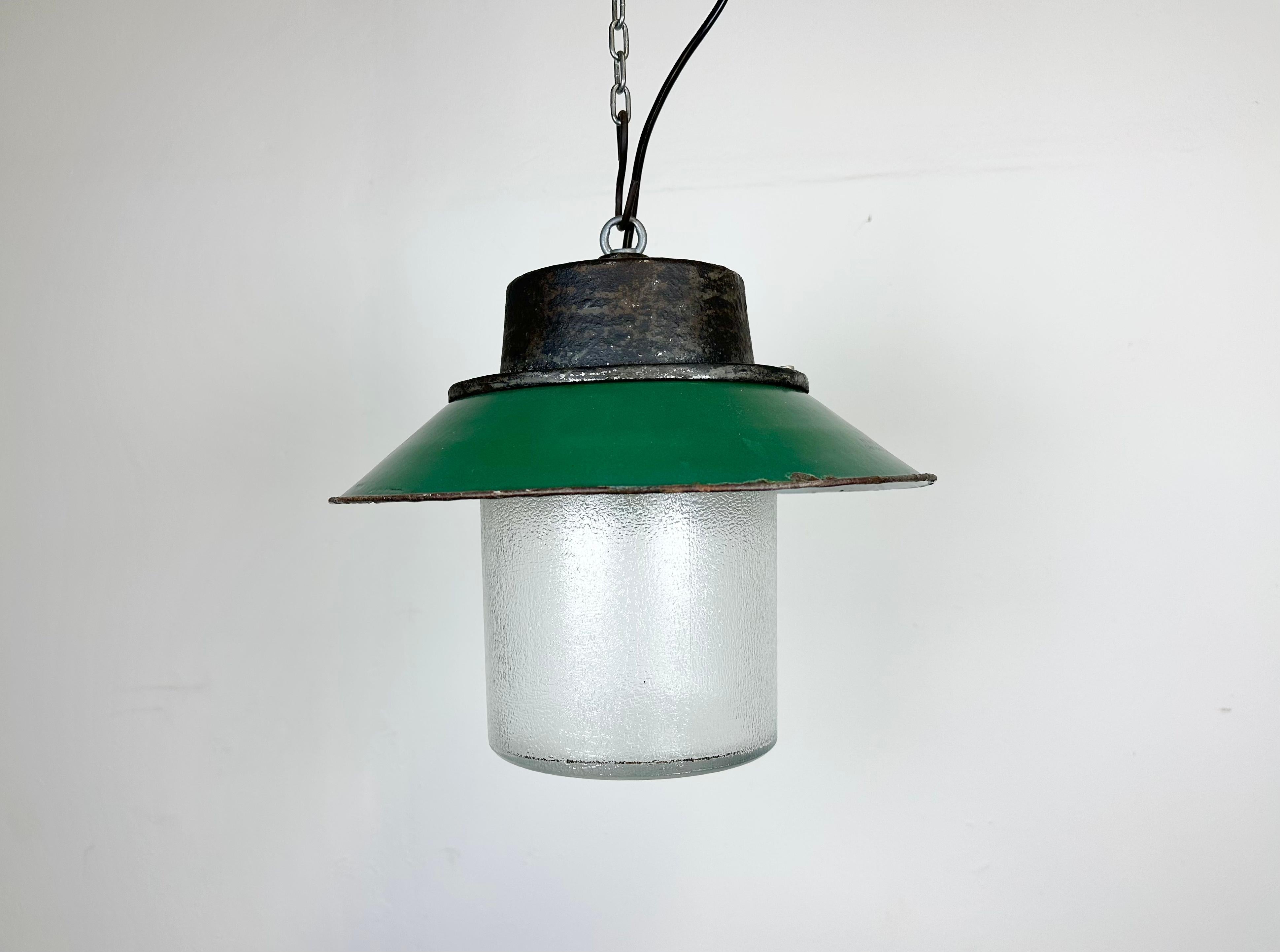 Industrial hanging lamp manufactured in Poland during the 1960s. It features a green enamel shade with a white enamel interior, a cast iron top and a frosted glass cover. The porcelain socket requires E 27/ E26 lightbulbs. New wire. The weight of