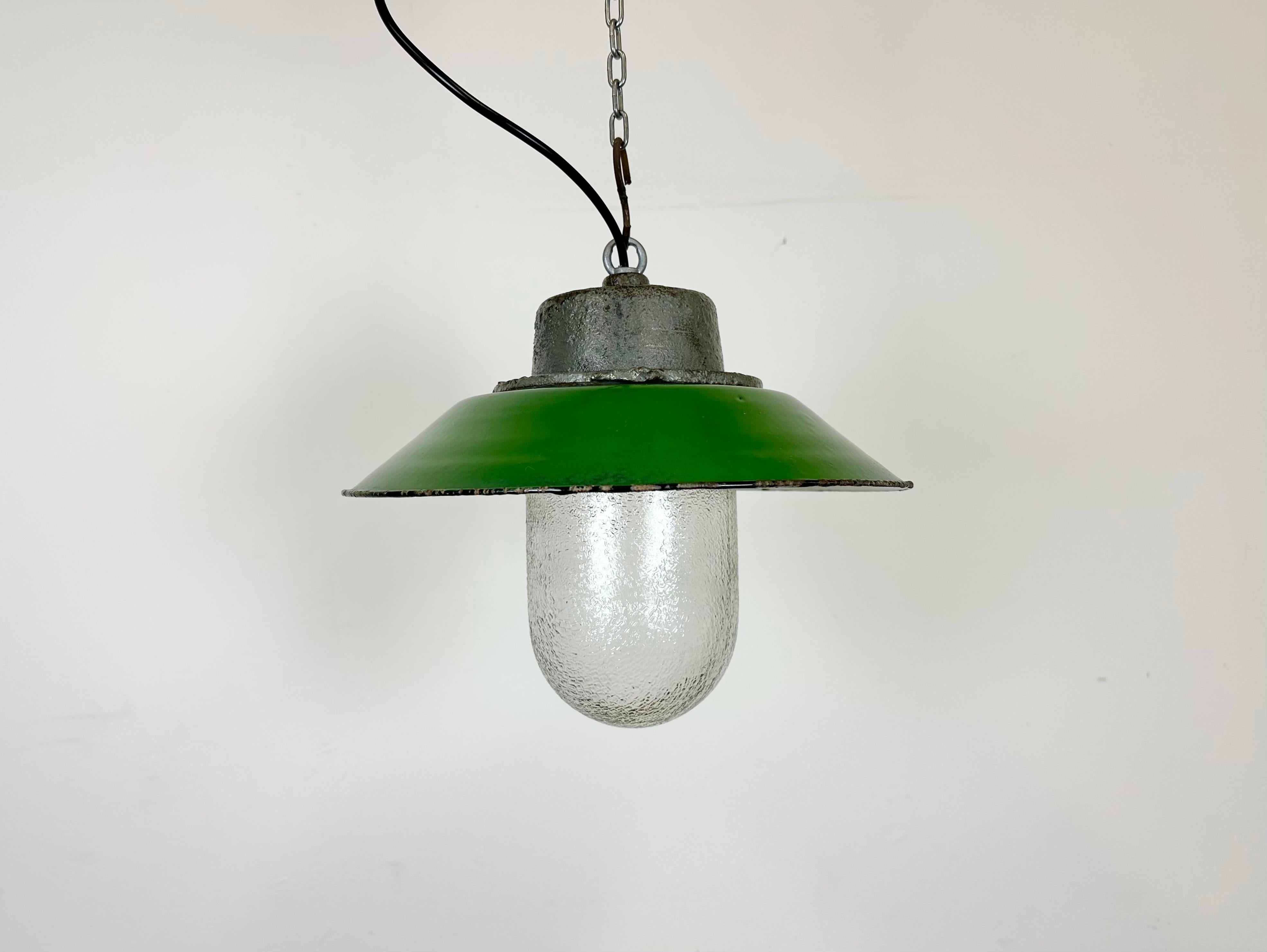 Hanging lamp manufactured by Przyslosc Sosnowiec in Poland during the 1960s. It features a green enamel shade with a white enamel interior, a cast iron top, and a frosted glass cover. The porcelain socket requires E 27/ E26 lightbulbs. New wire. The