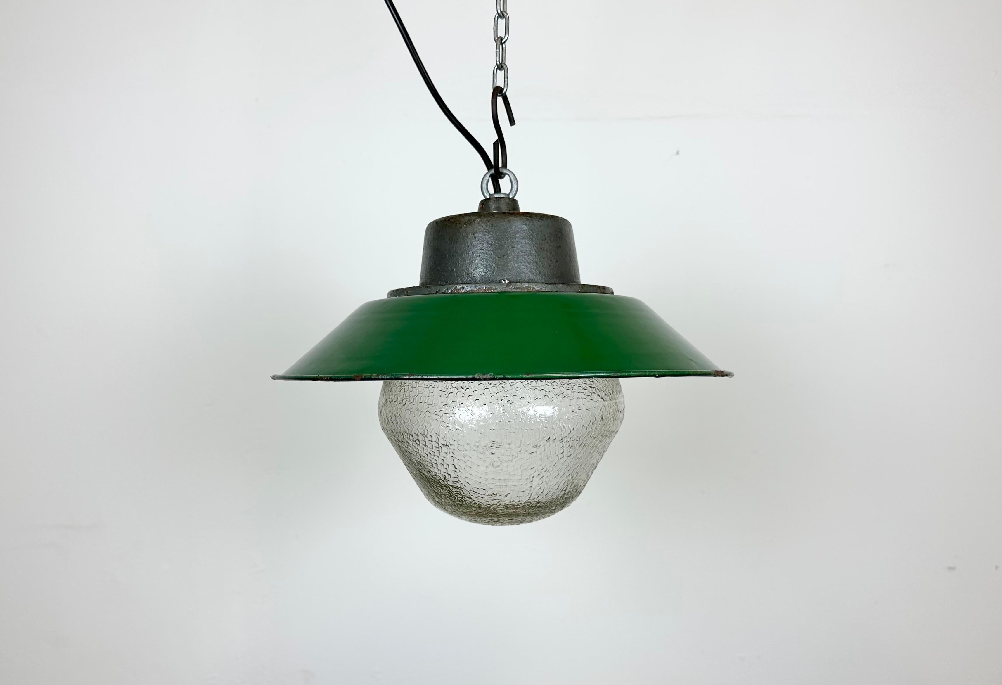 Hanging lamp manufactured by Przyslosc Sosnowiec in Poland during the 1960s. It features a green enamel shade with a white enamel interior, a cast iron top, and a frosted glass cover. The porcelain socket requires E 27/ E26 lightbulbs. New wire. The