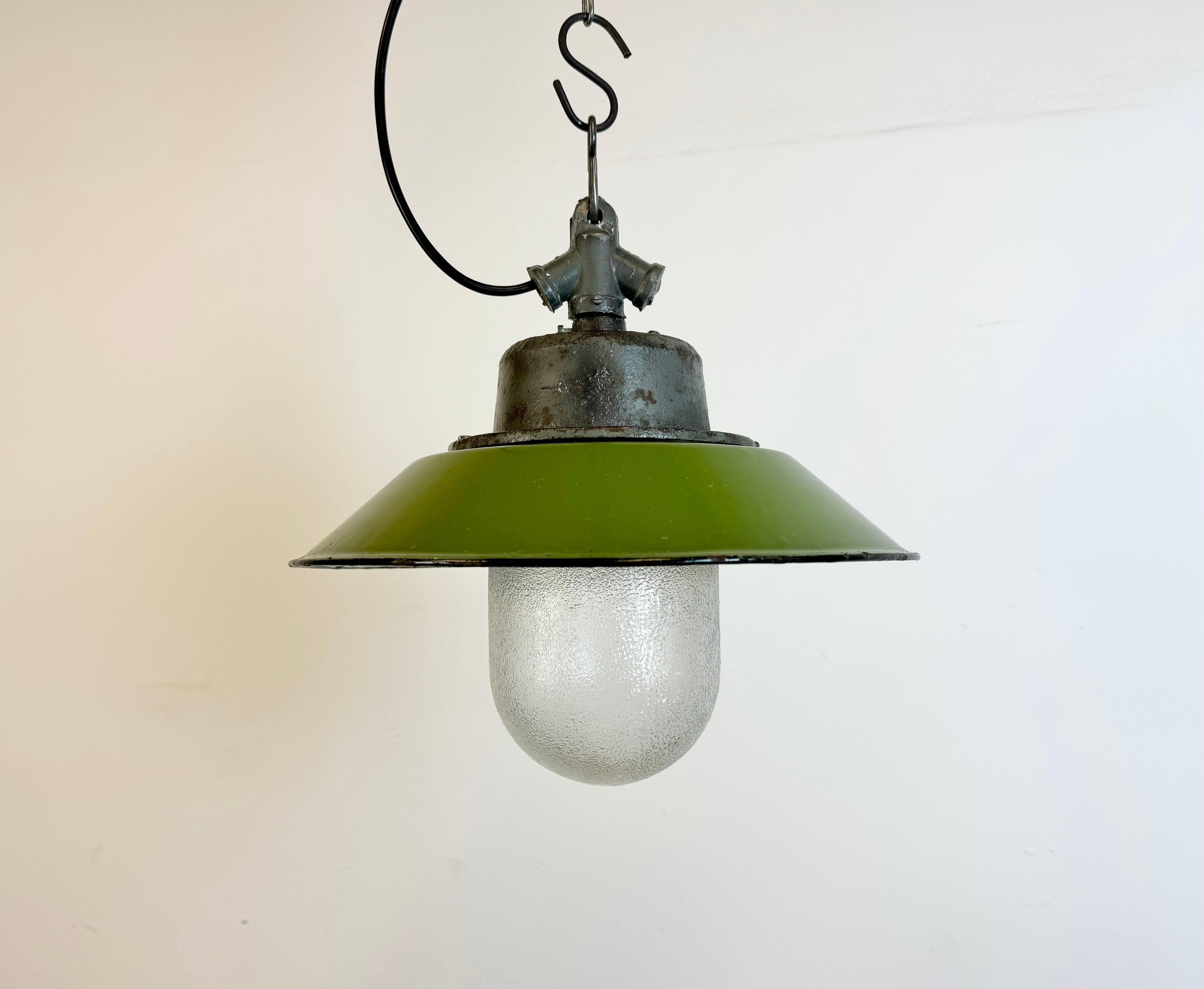 Industrial hanging lamp manufactured in Poland during the 1960s. It features a green enamel shade with white enamel interior, a cast iron top and a frosted glass cover. The porcelain socket requires standard E 27/ E26 lightbulbs .New wire. The