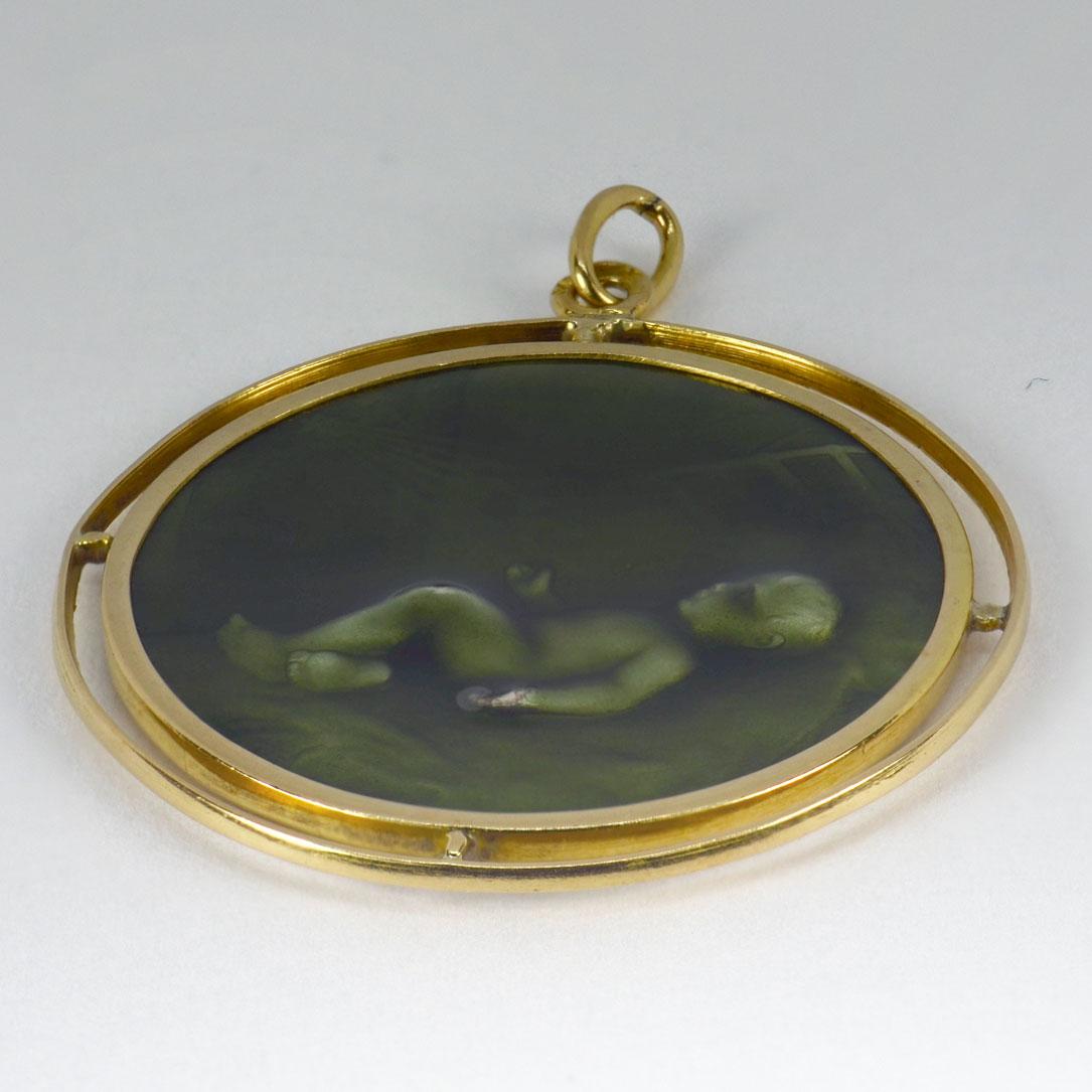 An 18 karat (18K) yellow gold charm pendant depicting a baby in an infant’s crib with rays of light streaming down onto it from a star. Stamped with the eagle’s head for French manufacture and 18 karat gold, and an unknown maker’s mark. Small enamel