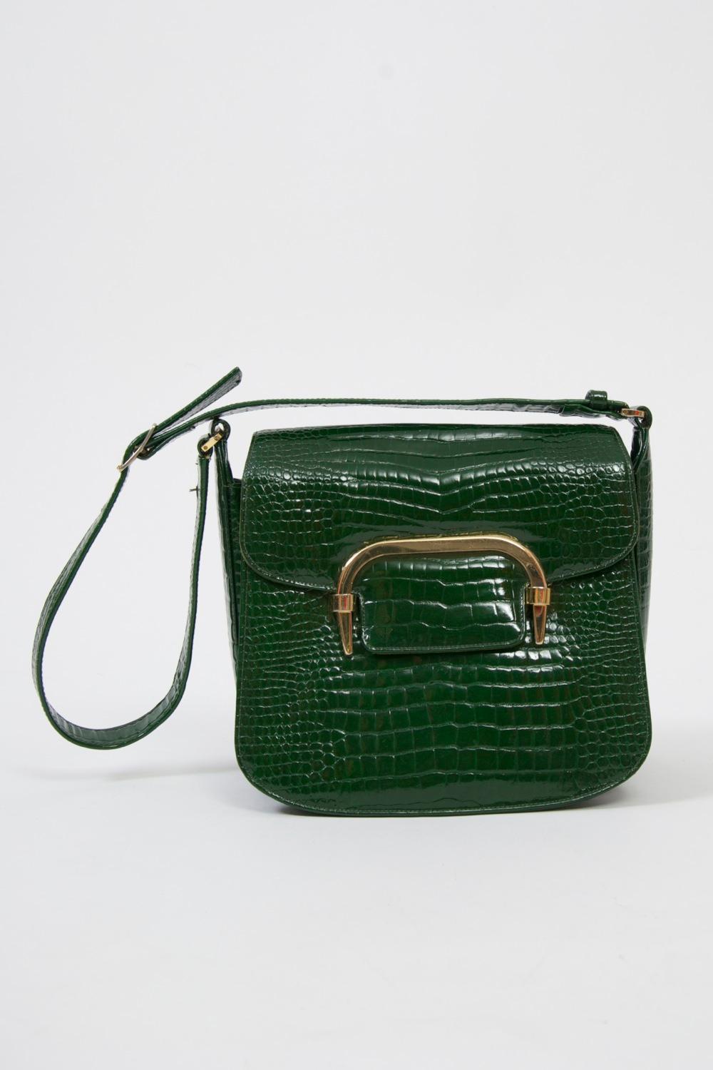 c.1970 shoulder bag in deep green, the texture pressed to simulate alligator, and featuring an interesting gold metal clasp on the flap that passes through two metal loops to close; the flap in lined in green suede. The wide interior is lined in