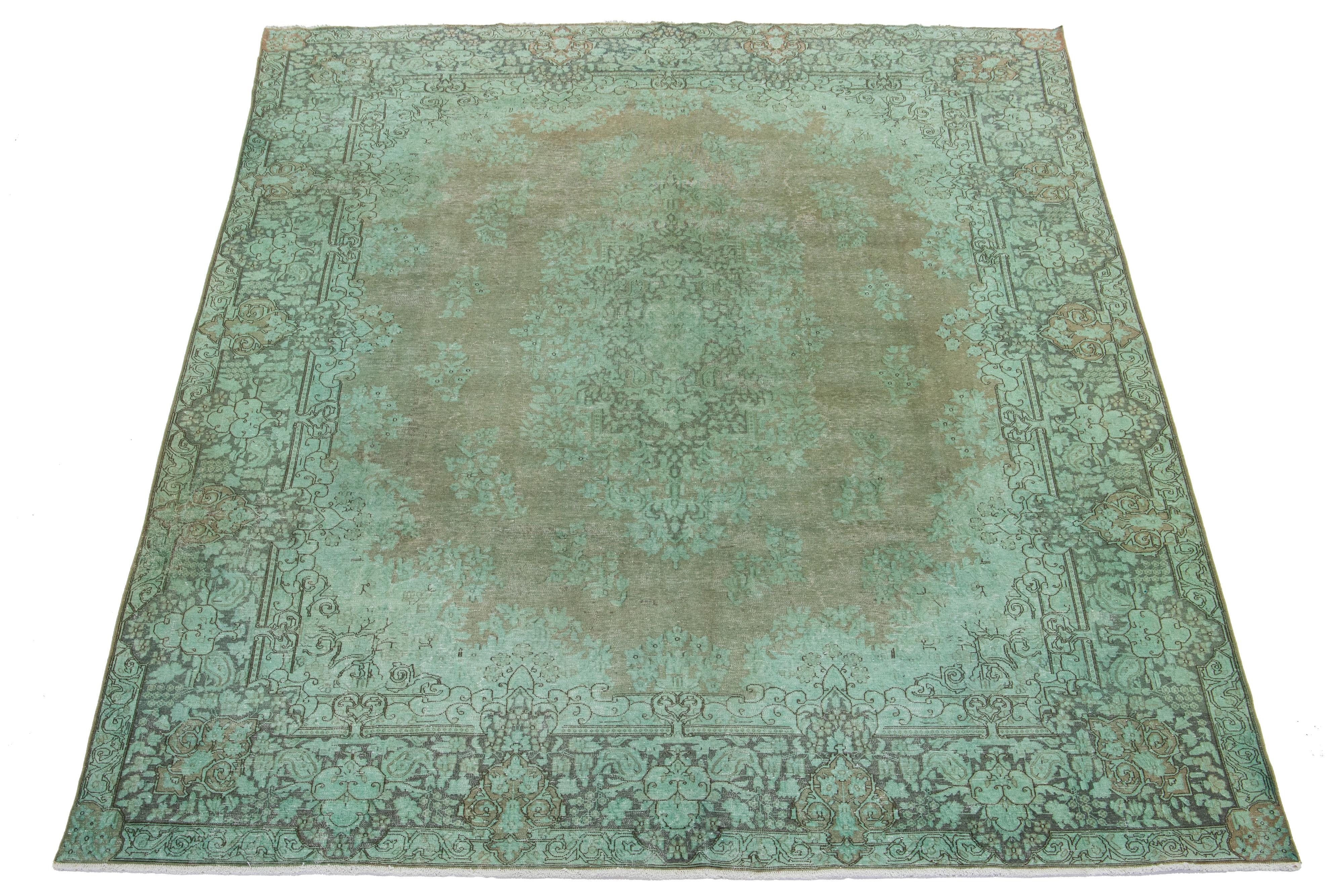 Dieser grüne, antike, handgeknüpfte Teppich aus persischer Wolle hat ein florales Medaillonmuster und graue Akzente.

Dieser Teppich misst 9'11'' x 12'6
