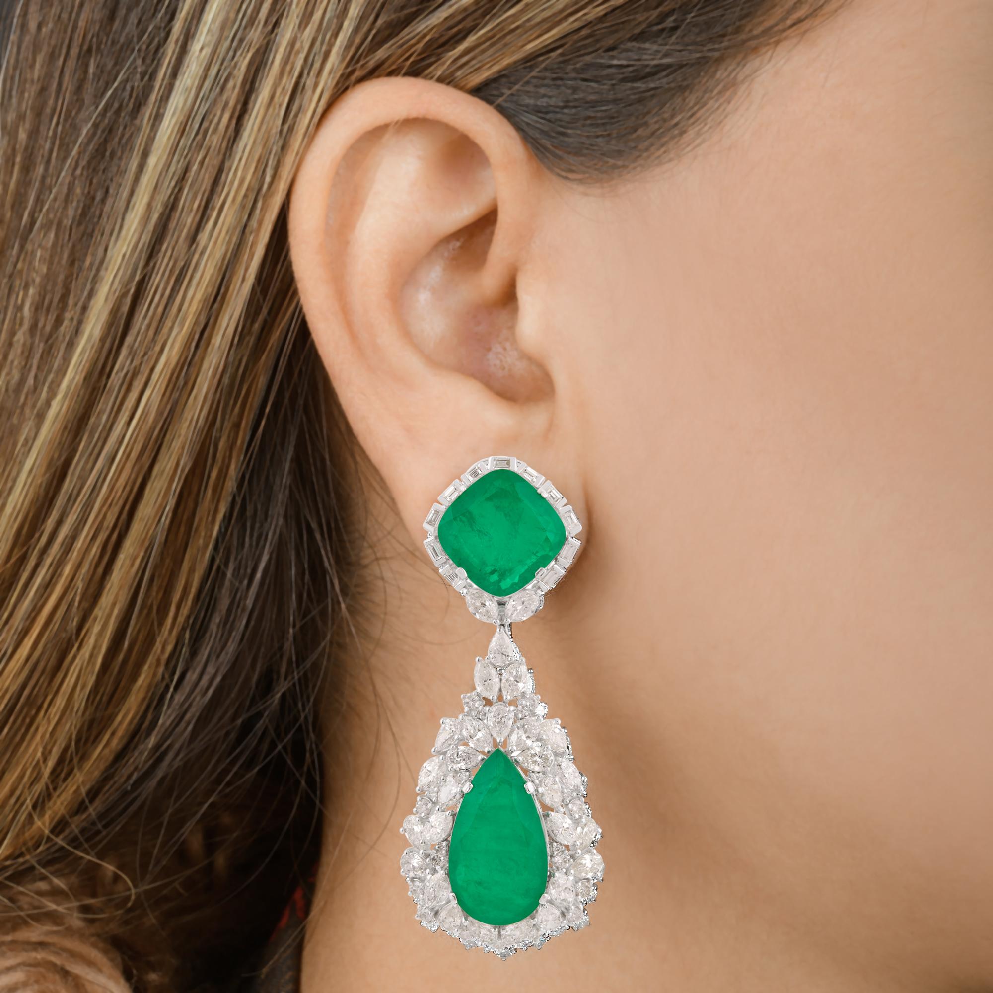  Boucles d'oreilles pendantes en or blanc 18 carats avec pierres précieuses vertes et diamants.
Un clou en pierre précieuse traitée verte de taille coussin se pose élégamment sur le lobe.
Une éblouissante pierre précieuse en forme de poire est
