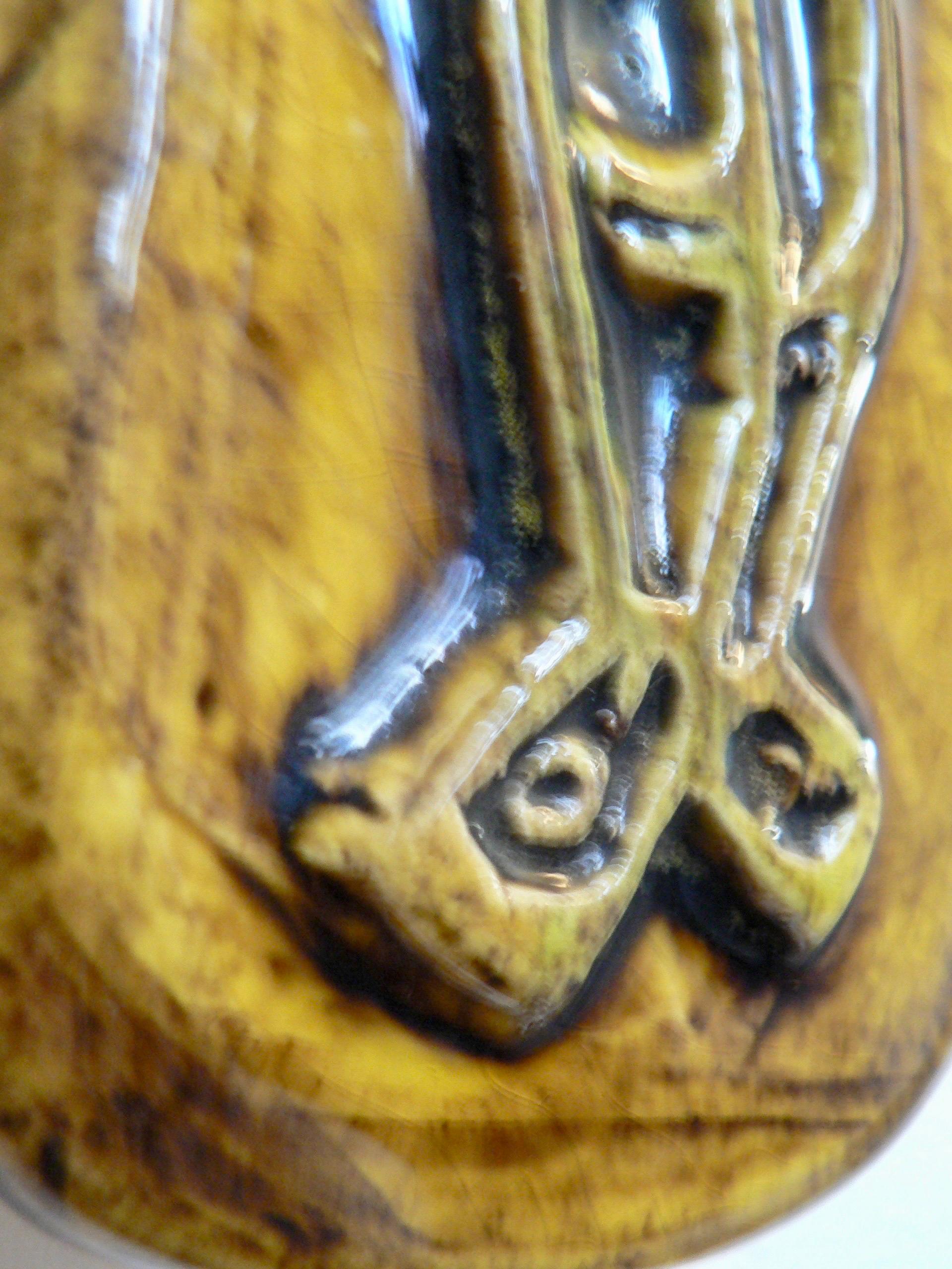 Le Crucifix de Georges Jouve, en faïence émaillée verte, est orné d'une inscription au sommet, portant les lettres 