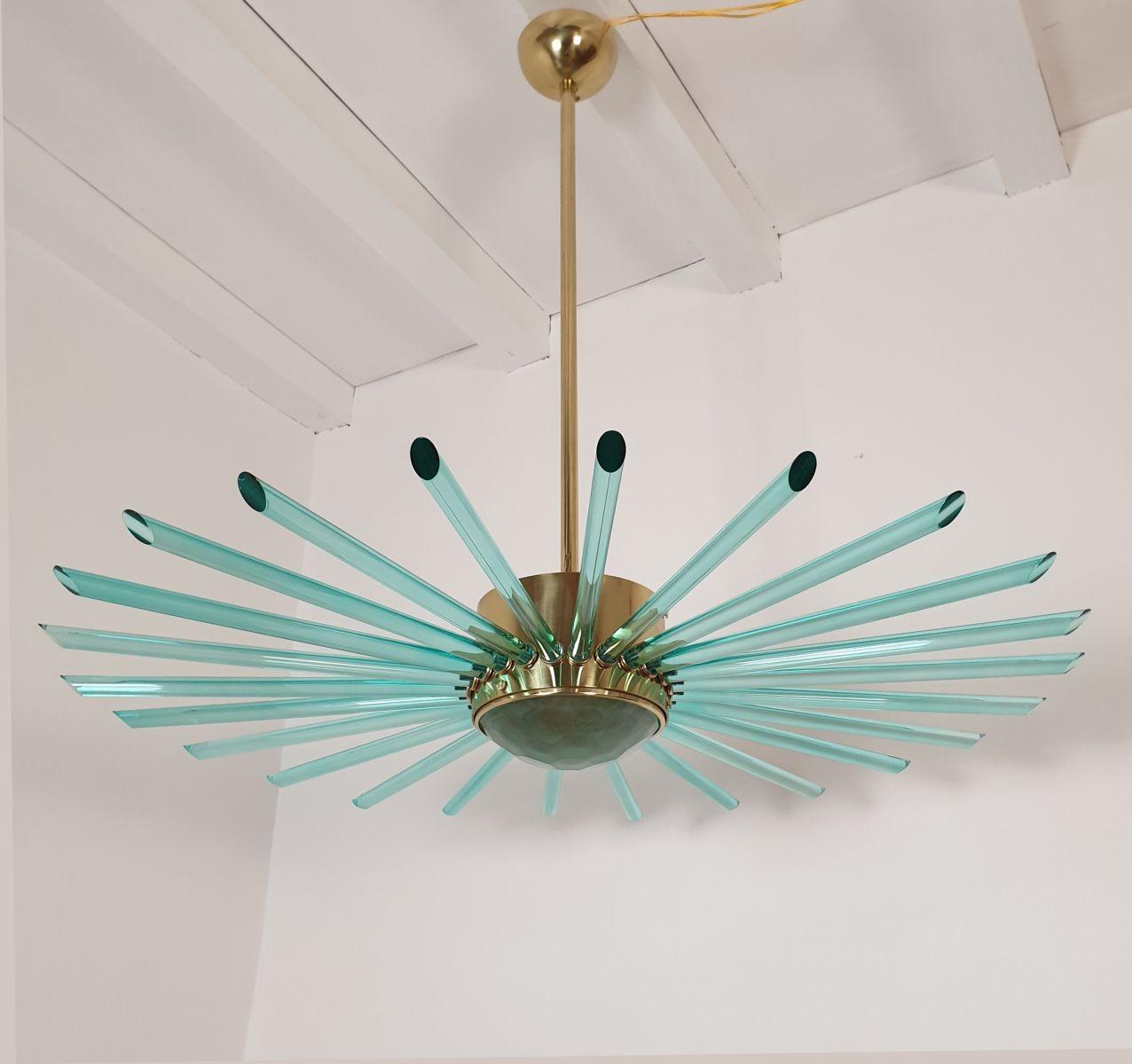 Large Mid Century Modern Sputnik chandelier, Italy 1980s.
The chandelier is made of a polished brass frame and green plain glass tubes.
The center bottom glass is pale green and translucent, nesting the light.
The chandelier is professionally