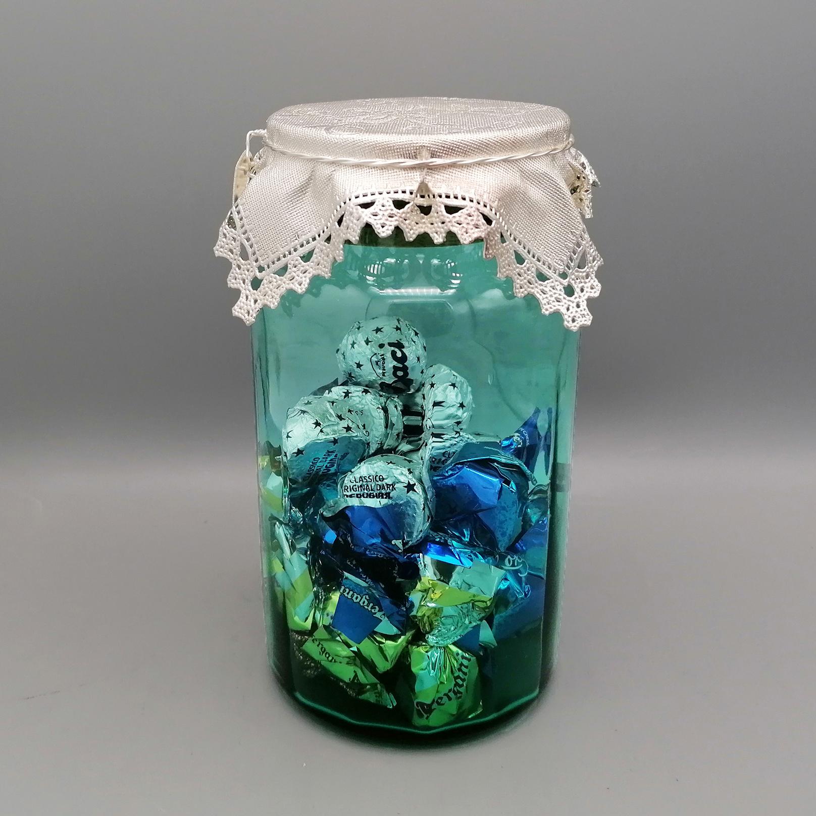 Green glass chocolate or sweets jar with 925 sterling silver lid in the shape of an embroidered handkerchief with lace border.

The jar, made of green optical glass, has a wooden cap completely covered in sterling silver in the shape of a small