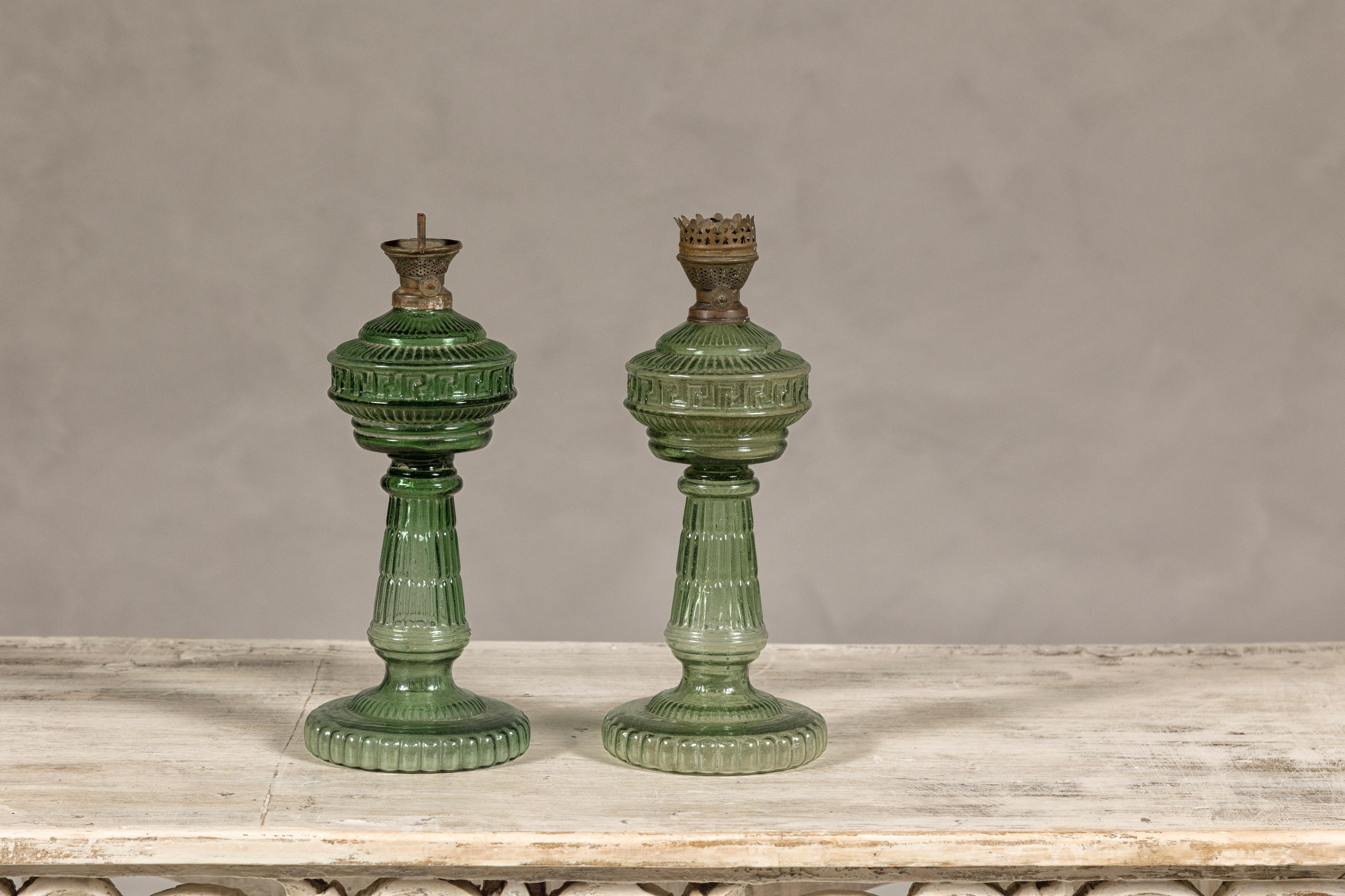 A near pair of green glass gas lights with meander friezes. Discover the unique charm and historical allure of this near pair of vintage Indian gas lights, a delightful find for those who appreciate the fusion of function and art. Crafted with green
