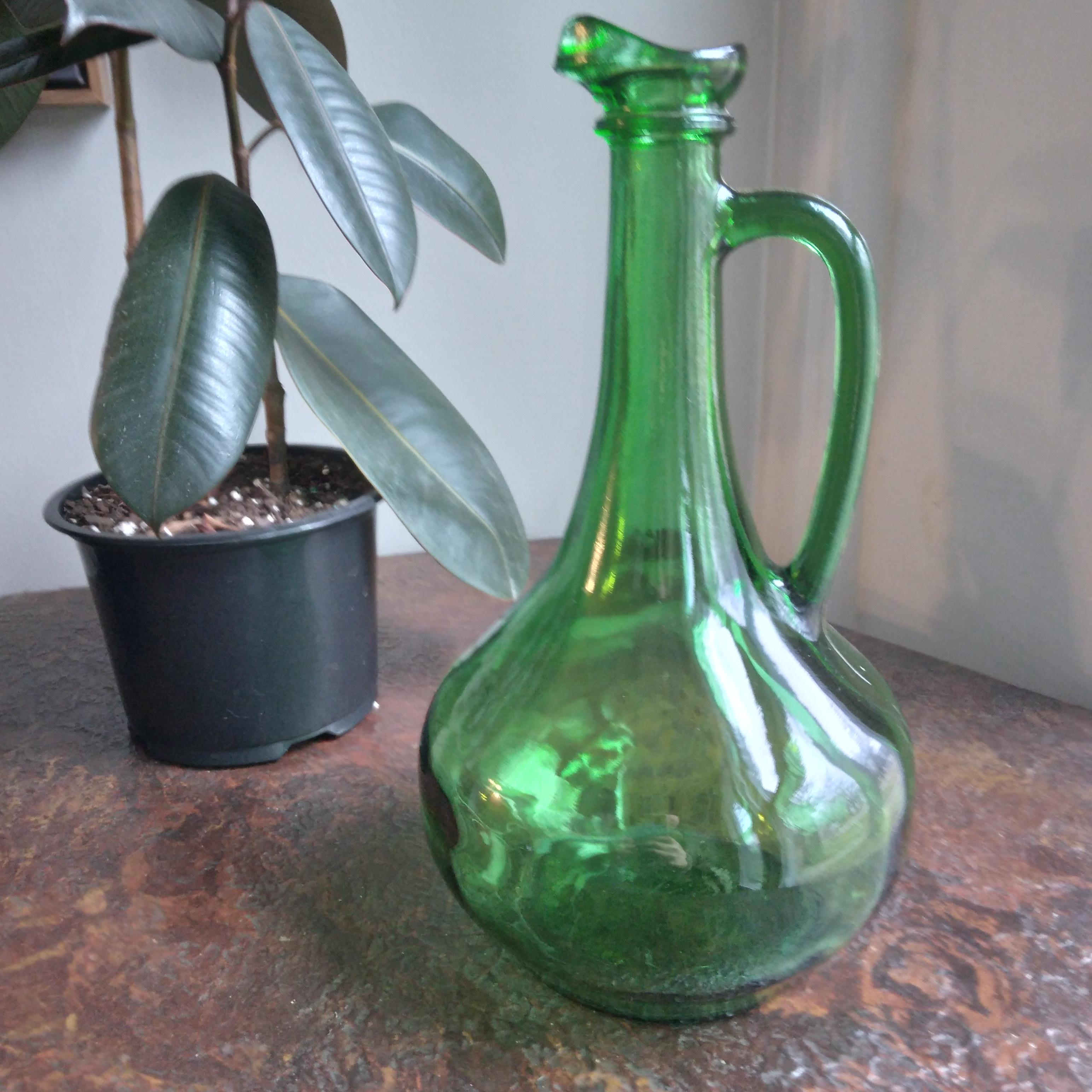 Graceful and green... this vintage wine decanter is simply stunning. We love her long neck, slender handle and generously curved base. The thick walled glass is in excellent condition. She would make an excellent pitcher or look great as a display