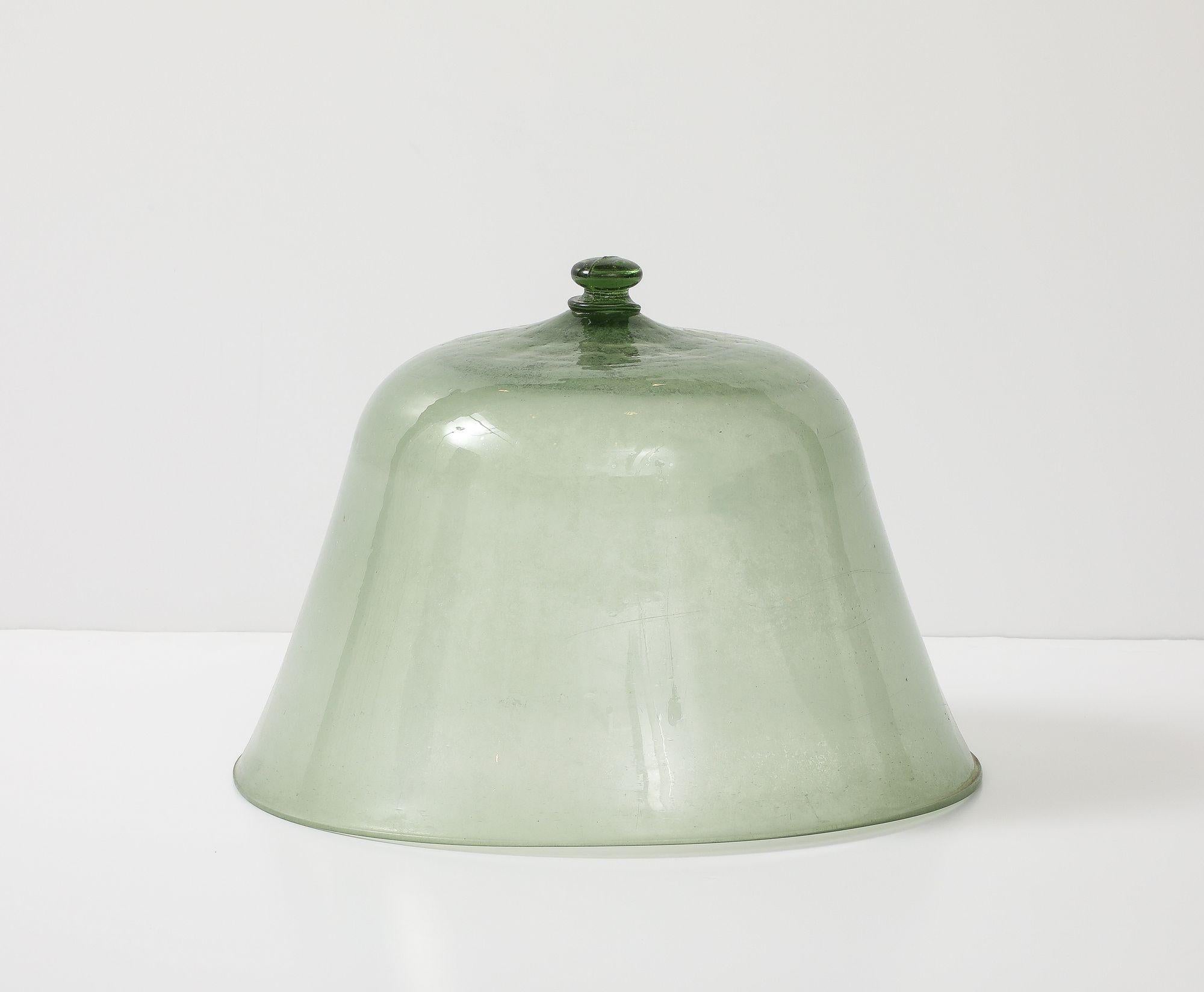 This green glass melon cloche with knob, crafted in 19th-century England, is a single piece of hand-blown glass, featuring a distinct original intact knob for easy handling. Traditionally used in gardens and greenhouses, this elegant cloche