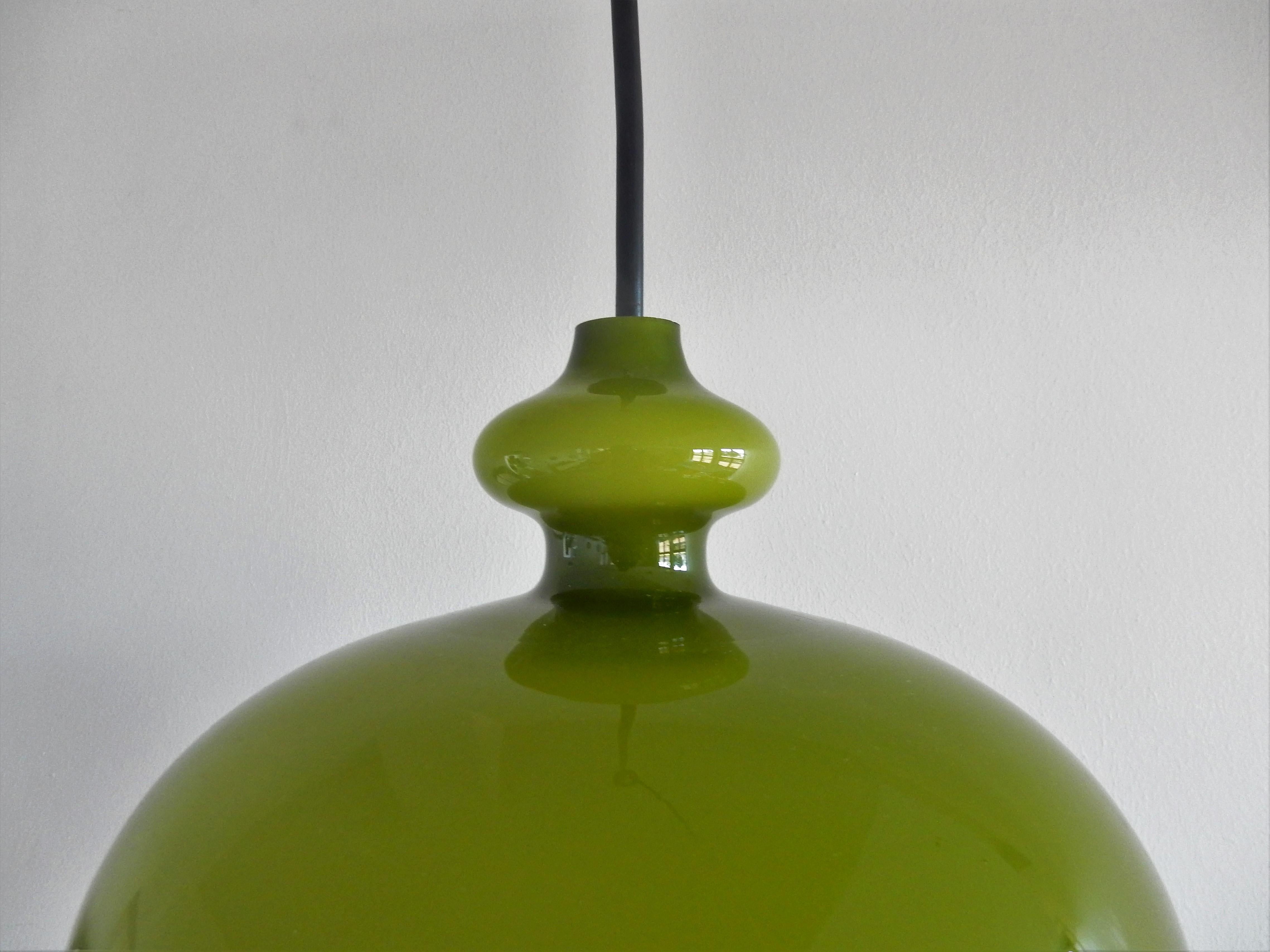 This beautiful round shaped glass pendant lamp was designed by Hans-Agne Jakobsson for Svera in the 1960s. It has a warm green colored glass shade with an opaline inside for a beautiful softened light. This lamp is in a very good condition with