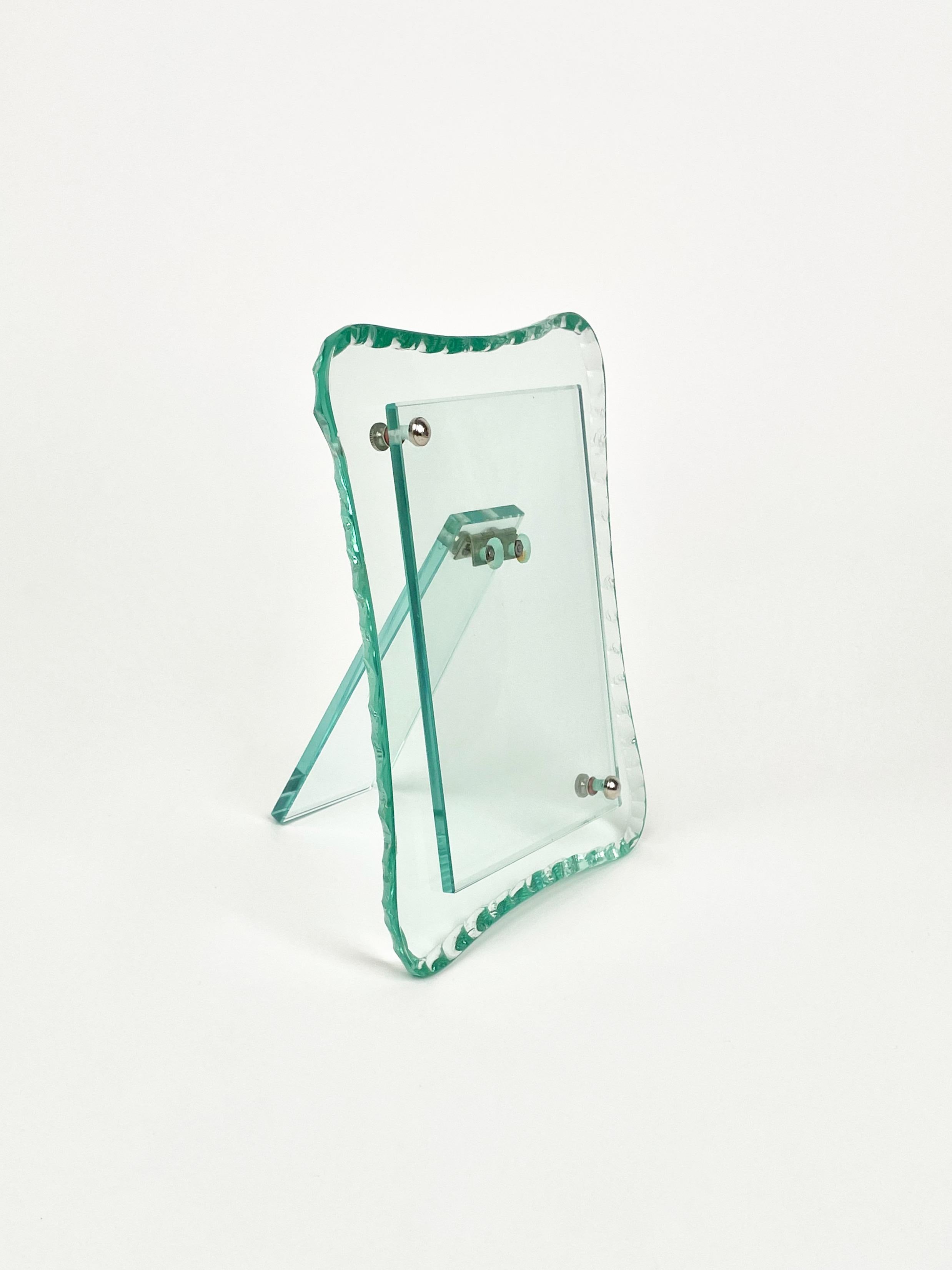 Rectangular picture frame in green glass decorated with chiseled edges and two silver metal buttons attributed to Fontana Arte.

Made in Italy in the 1960s.