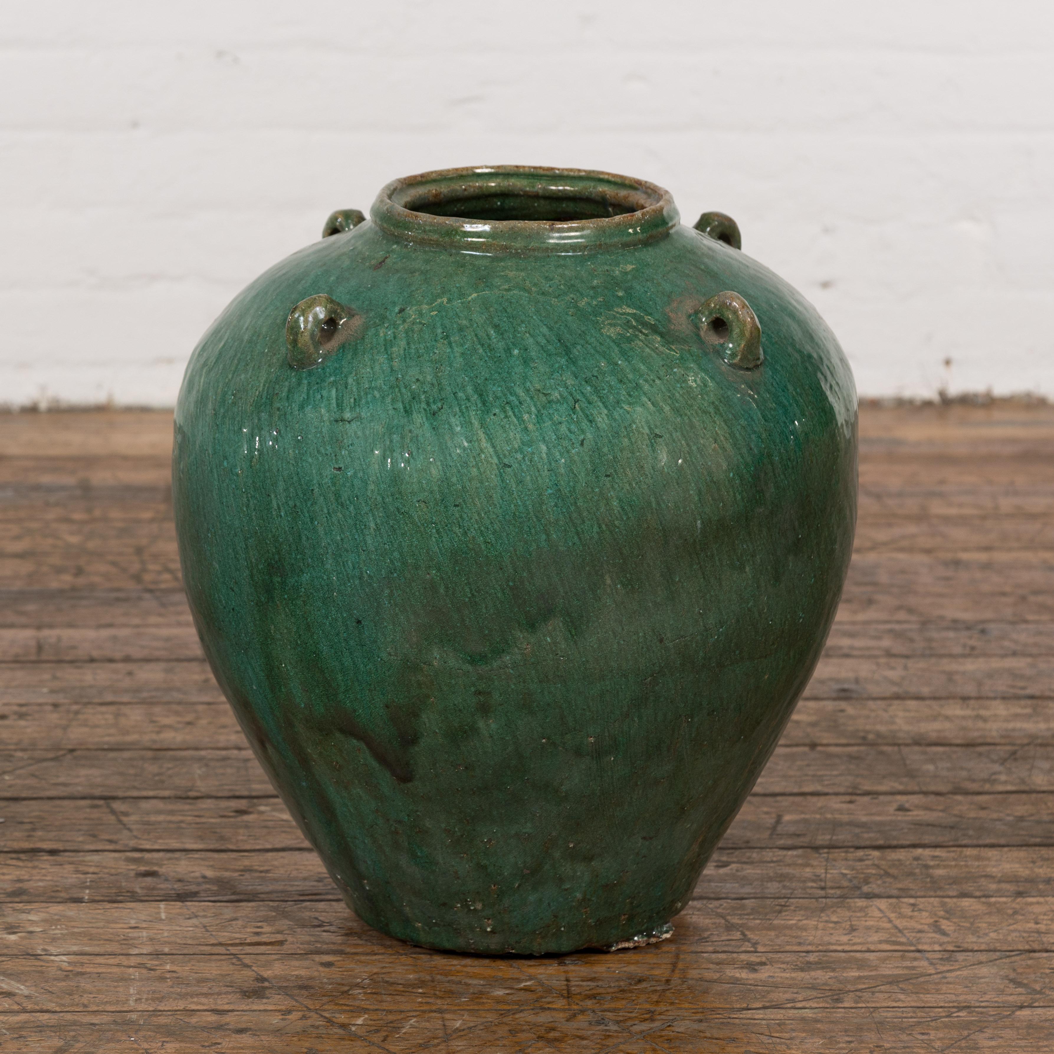 A Chinese antique late Qing Dynasty period green glaze Hunan jar from the early 20th century with petite swan neck loop handles, subtle wave effects and tapering lines. This late Qing Dynasty period Hunan jar, originating from the early 20th