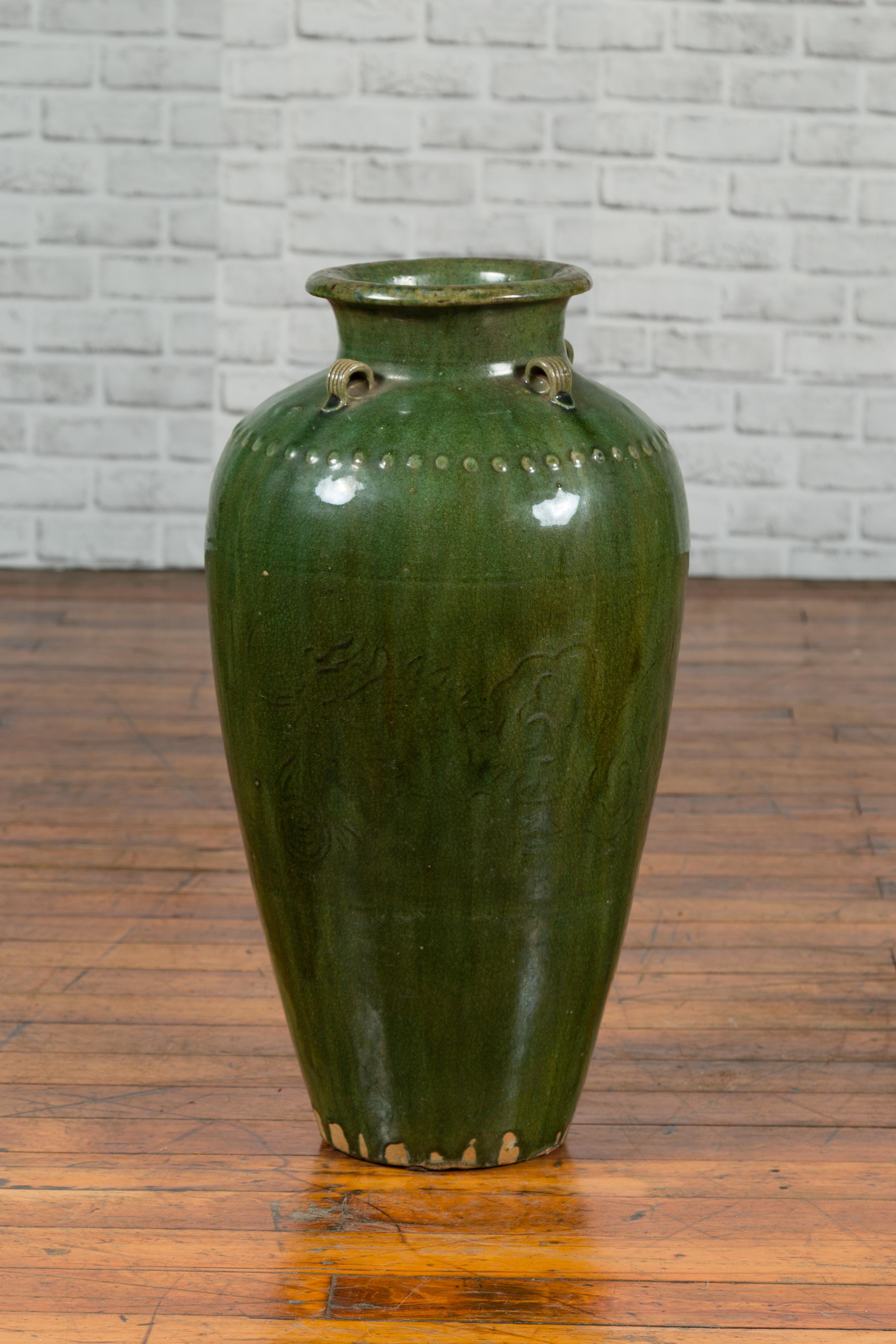 A green glazed Martaban water jug from the 19th century, with petite handles and faint decor. Charming us with its green glaze perfectly accented with petite beads on the upper body, this Martaban water jug is adorned with a series of petite loop