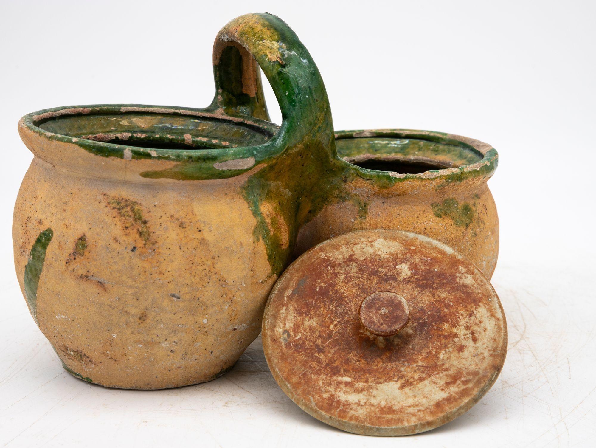 This 19th-century French Porte-Dîner, a shepherd’s lunch holder, features two stacked bowls joined by a gracefully arched handle and finished in a rich green glaze. Its rustic form and utilitarian elegance reflect the simplicity of rural life in