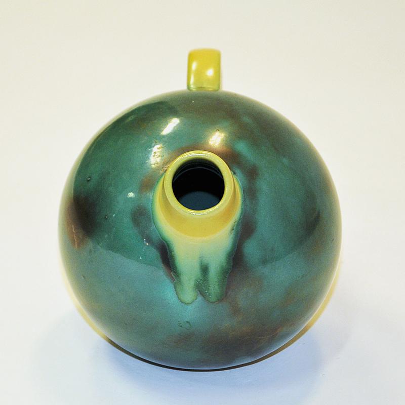 Lovely matt green glazed colored tea pot by Upsala Ekeby in 1930s Sweden. Round delicate ball shaped design with a yellow half circled handle and spout. Good vintage condition and perfect Scandinavian design. Marked Ekeby 323 underneath the