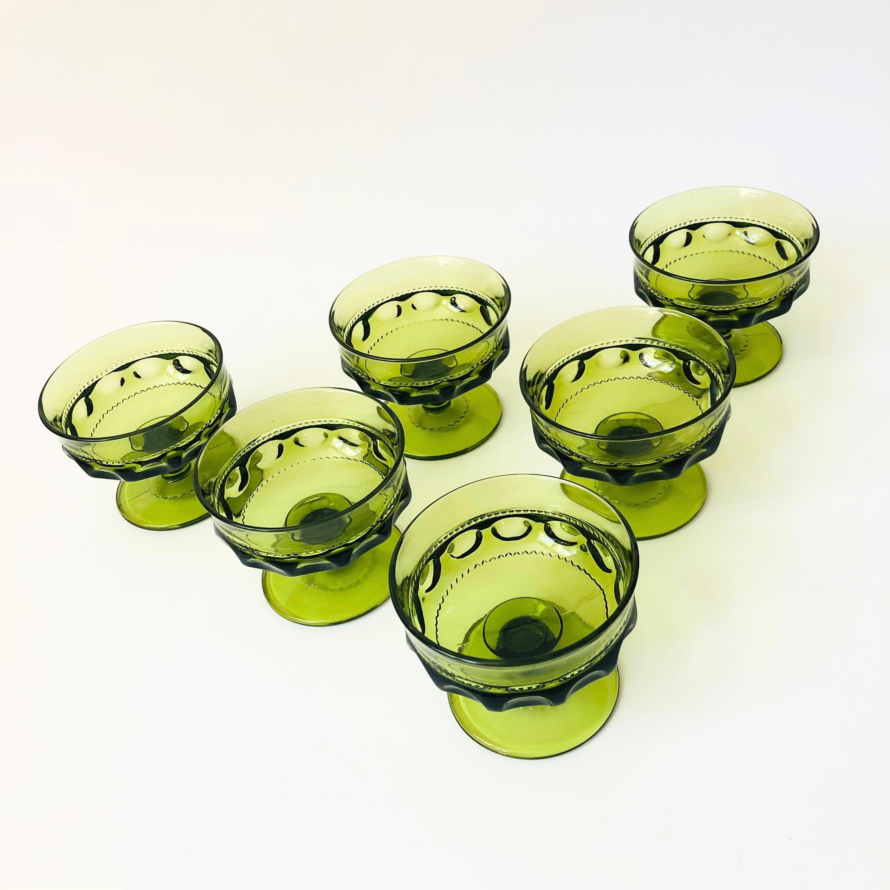 A set of 6 vintage coupe glasses in an ornate design in green colored glass. Made in the King's Crown pattern by Indiana Glass. Perfect for a glass of champagne.

