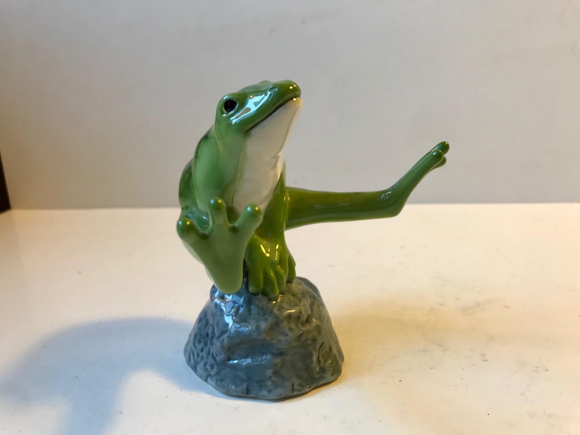Designed by Danish sculptor Allan Therkelsen, this unusual Royal Copenhagen figurine depicts a Green Frog sitting on a rock ready to jump. It is a part of the 