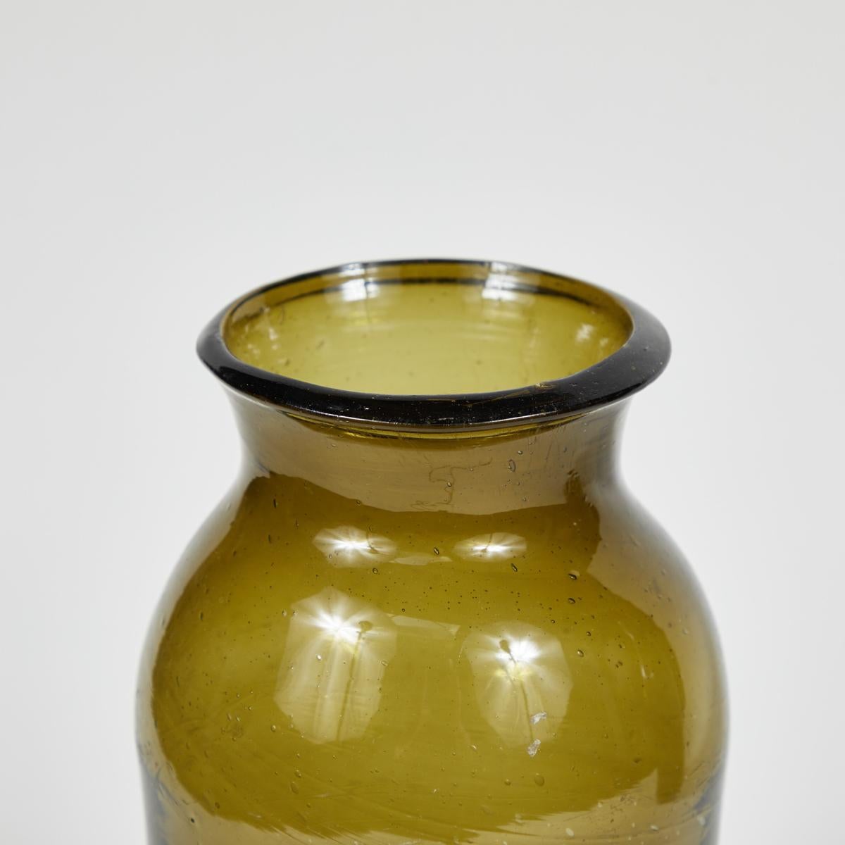 French 19th-century hand-blown glass bottle in beautiful deep olive hue. Rustic and artisanal, this versatile object can be used any number of ways—as a decanter, as a vase, or clustered with other bottles to add height, dimension, and a rich