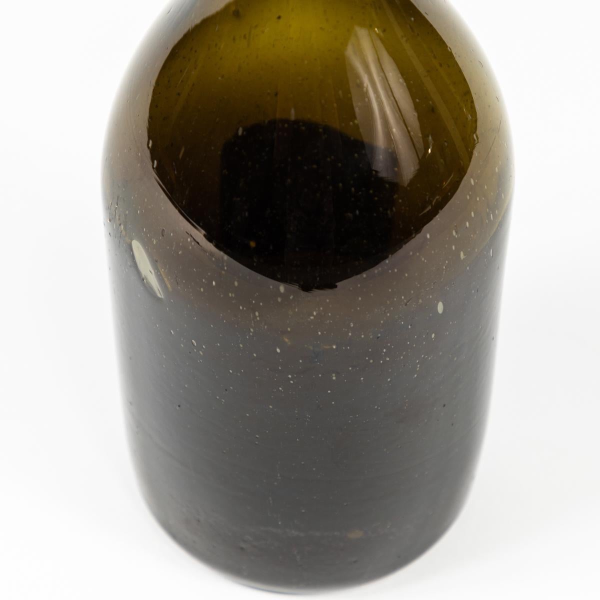 Bouteille en verre soufflé à la main du 19e siècle dans une belle teinte olive profonde. Rustique et artisanal, cet objet polyvalent peut être utilisé de multiples façons - comme carafe, comme vase, ou associé à d'autres bouteilles pour donner de la