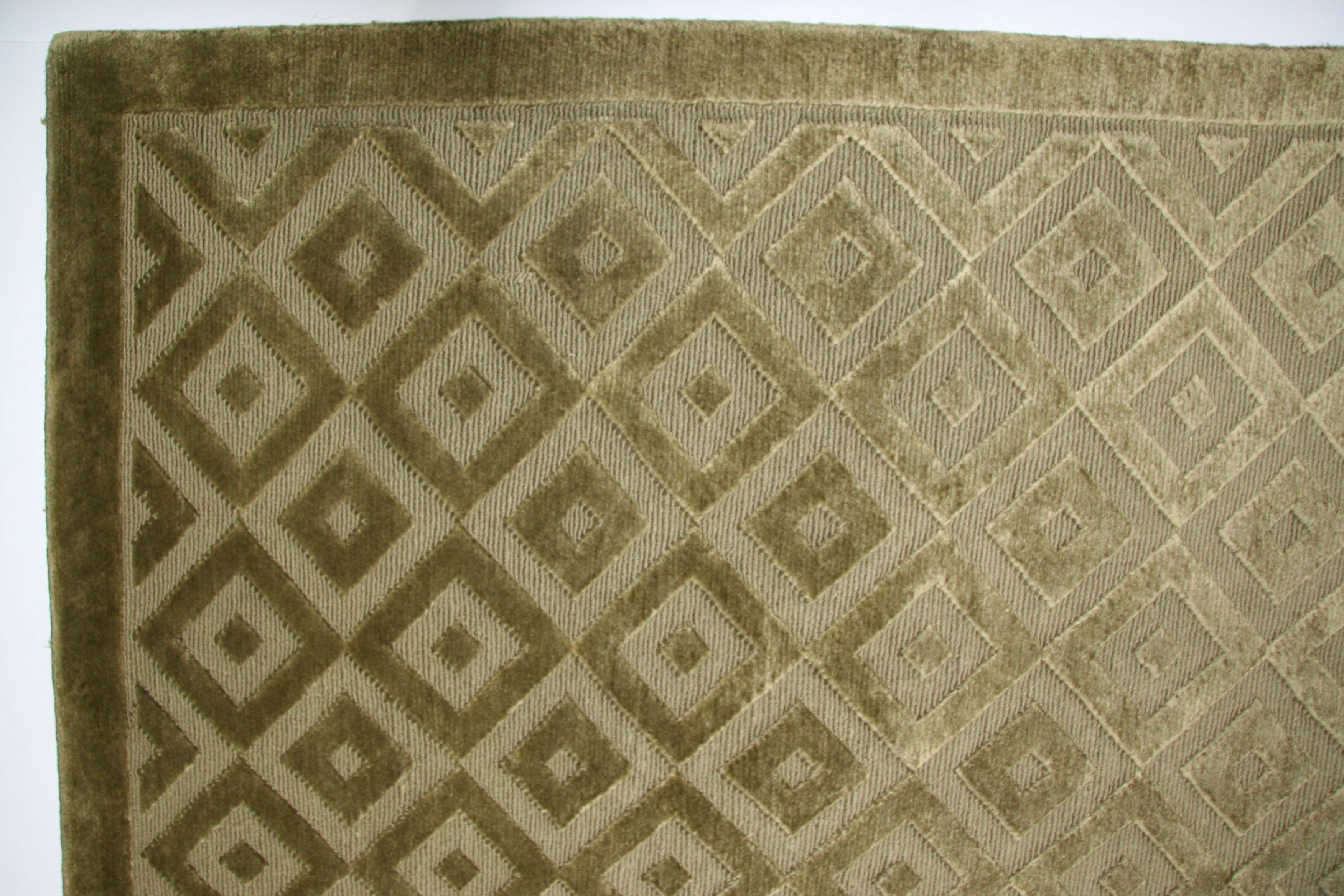 Looped and cut fibers combine to create varying textures in this contemporary wool and silk area rug. The hand-knotting technique creates distinct 'light' and 'dark' sides (shown here) when viewed from opposing sides. Green and taupe/biege tones.