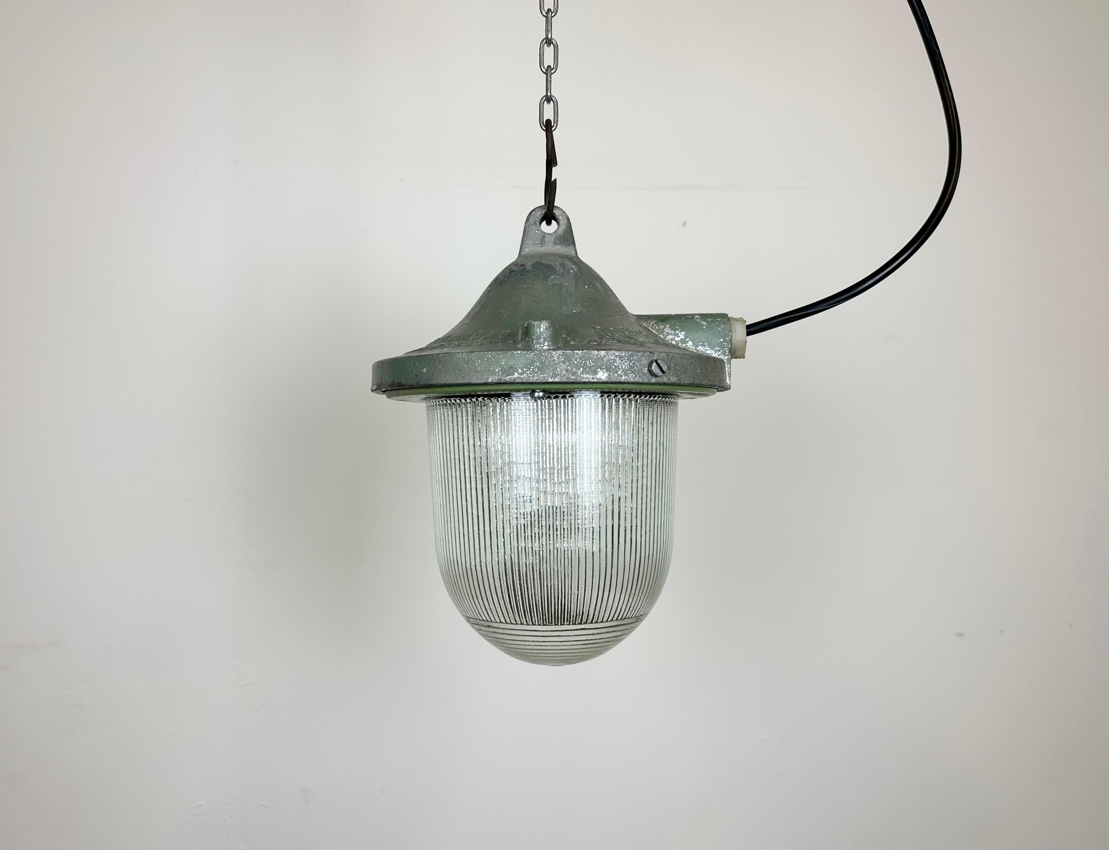 Green industrial lamp made by Polam Gdansk in Poland during the 1960s. It features a cast aluminium body and a striped glass. The porcelain socket requires E 27/ E 26 lightbulbs. New wire. The weight of the lamp is 2.5 kg.