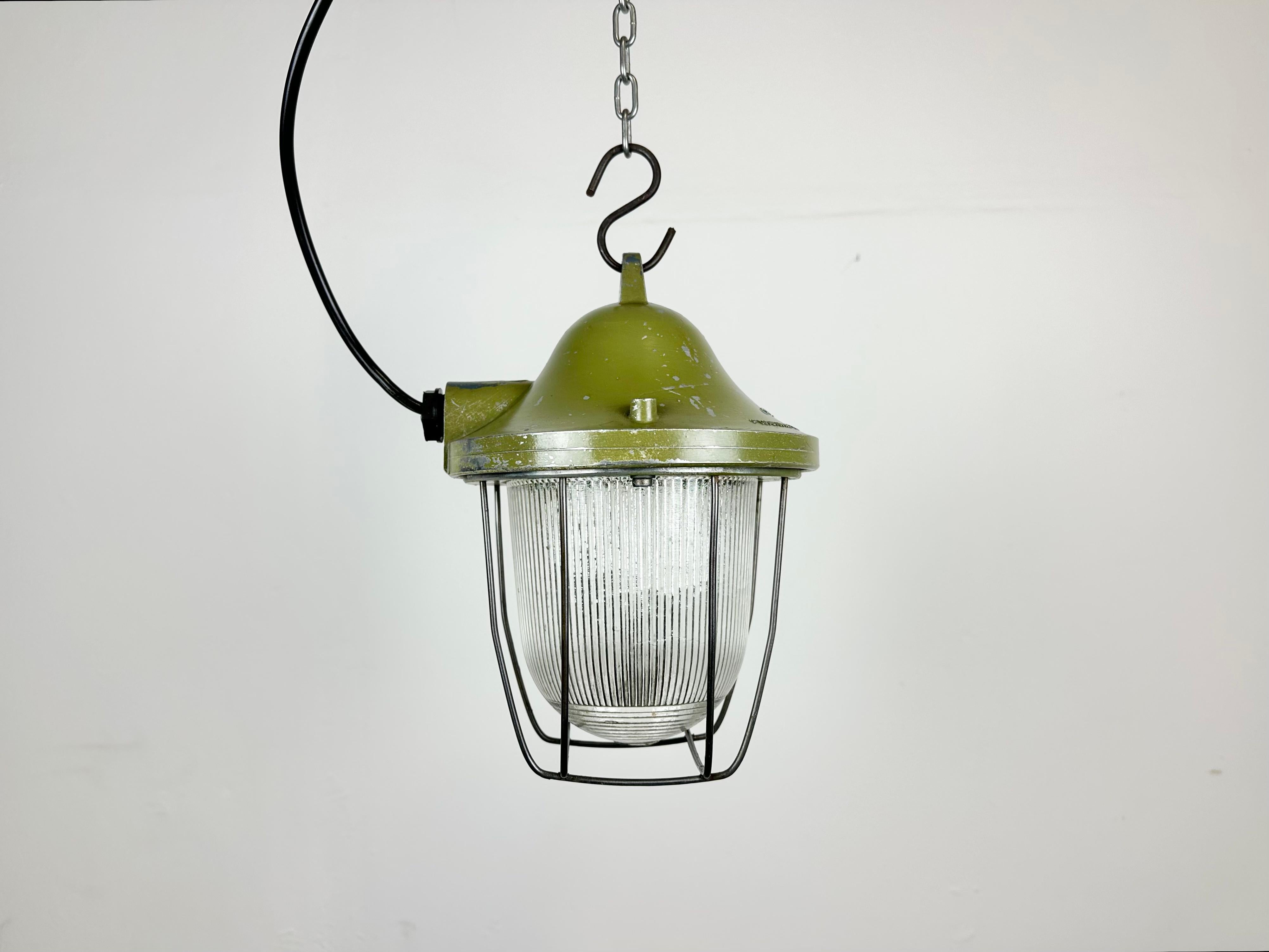 Green industrial lamp made by Polam Gdansk in Poland during the 1960s. It features a cast aluminium body, an iron cage and striped glass. The porcelain socket requires E 27/ E 26 lightbulbs. New wire. The weight of the lamp is 1,6 kg.
  