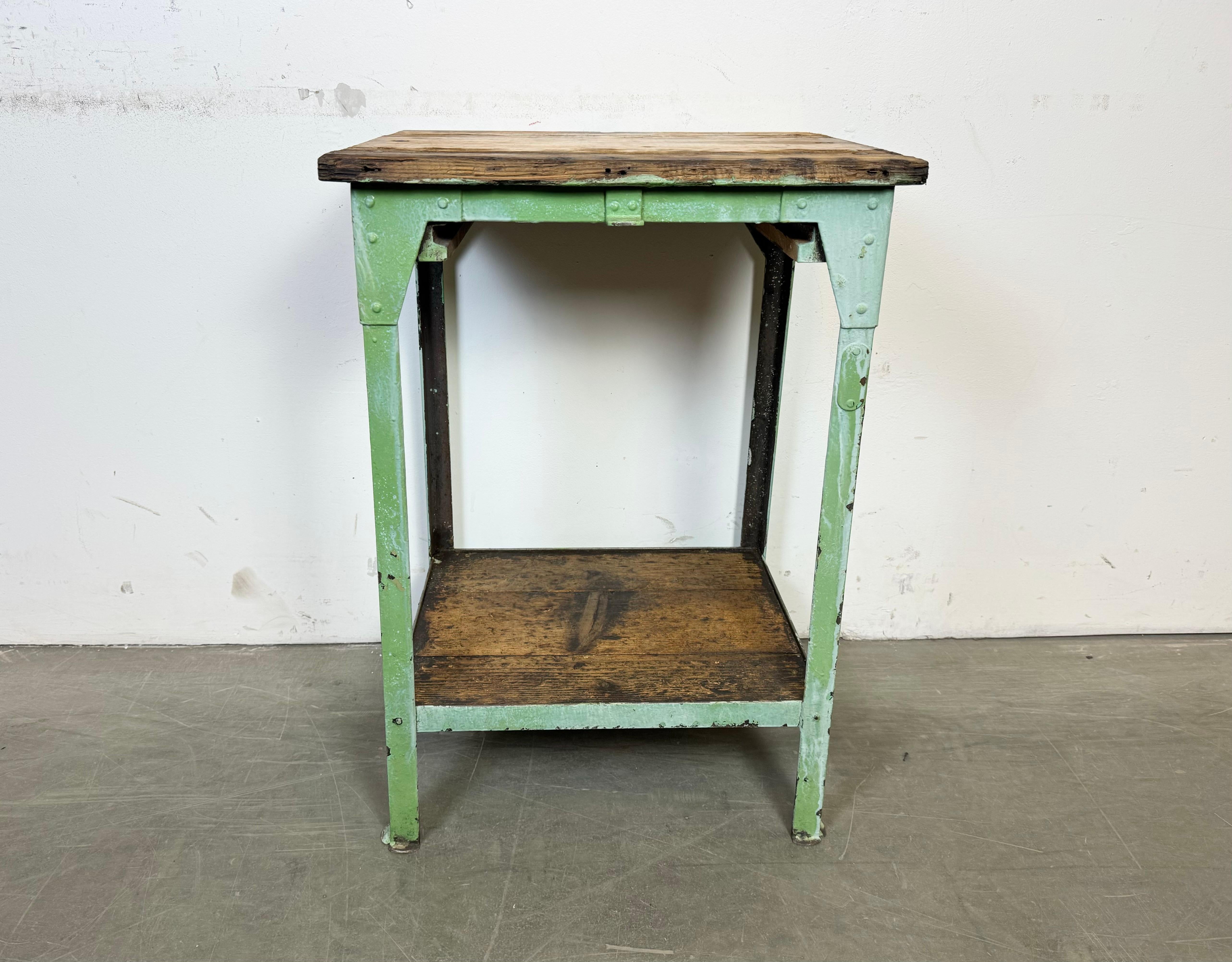 Questo tavolo industriale vintage è stato realizzato nell'ex Cecoslovacchia negli anni Cinquanta. Presenta una struttura rivettata in ferro verde e un piatto e un ripiano in legno.
Il peso del tavolo è di 16 kg.