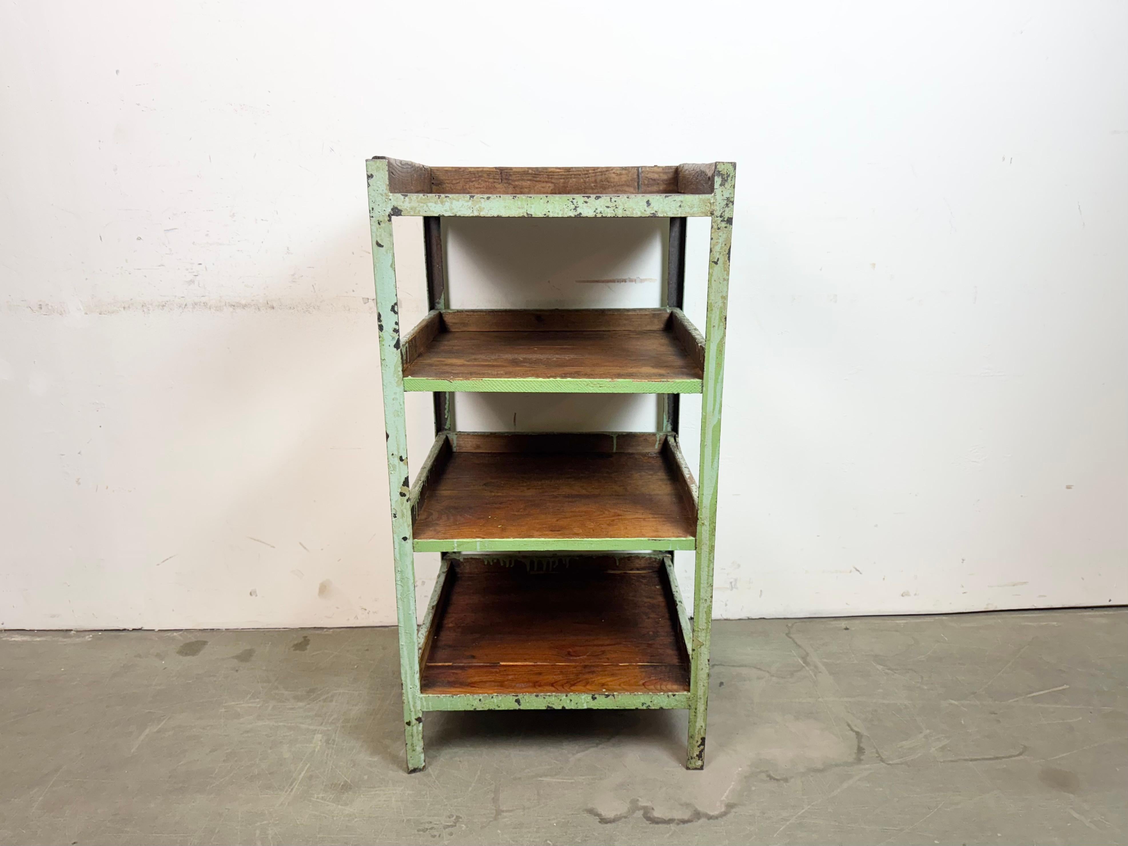 Etagère industrielle des années 1960. Elle est composée d'une structure en fer vert et de quatre étagères en bois. Le poids de l'étagère est de 25 kg.