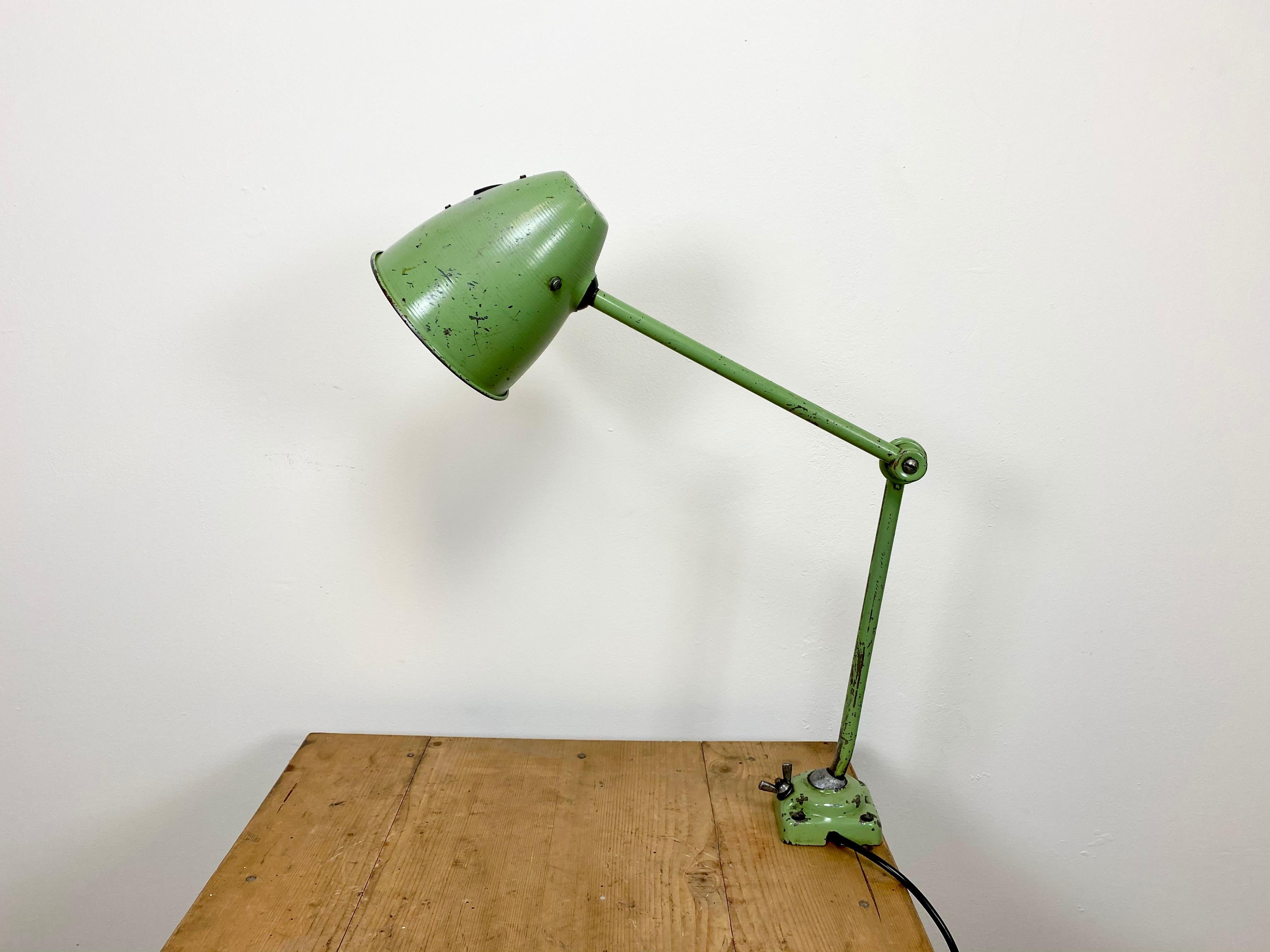 This green industrial style iron table lamp was made in former Czechoslovakia. It has an adjustable shade, three adjustable joints, a porcelain socket for E 27 light bulbs and new wire. The switch is situated directly on the shade. Fully functional.