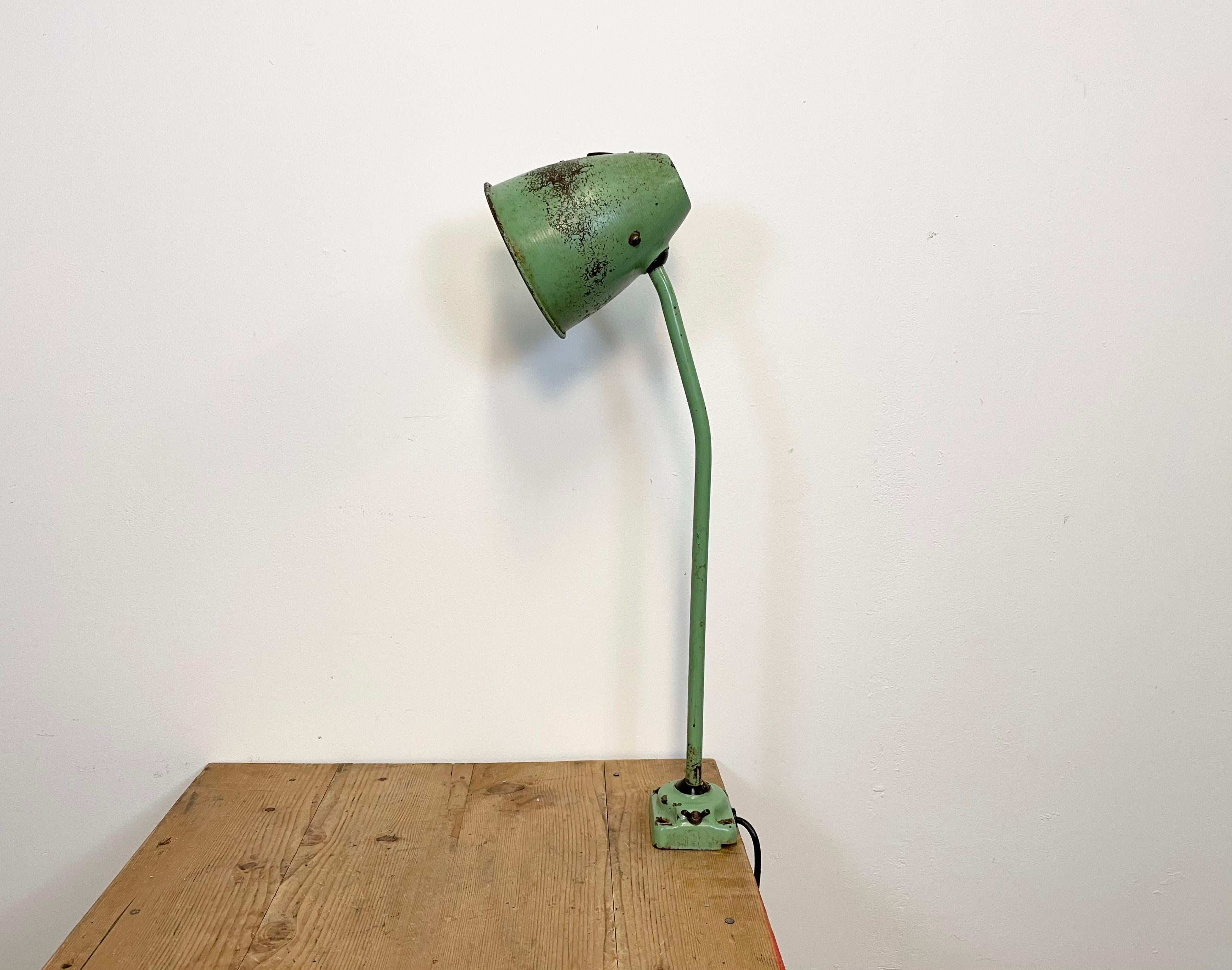 Green industrial adjustable workshop  table lamp was made in former Czechoslovakia during the 1960s. It features an iron shade ,base and arm with two adjustable joints. The porcelain socket requires standard E 27/ E26 light bulbs.New wire. The