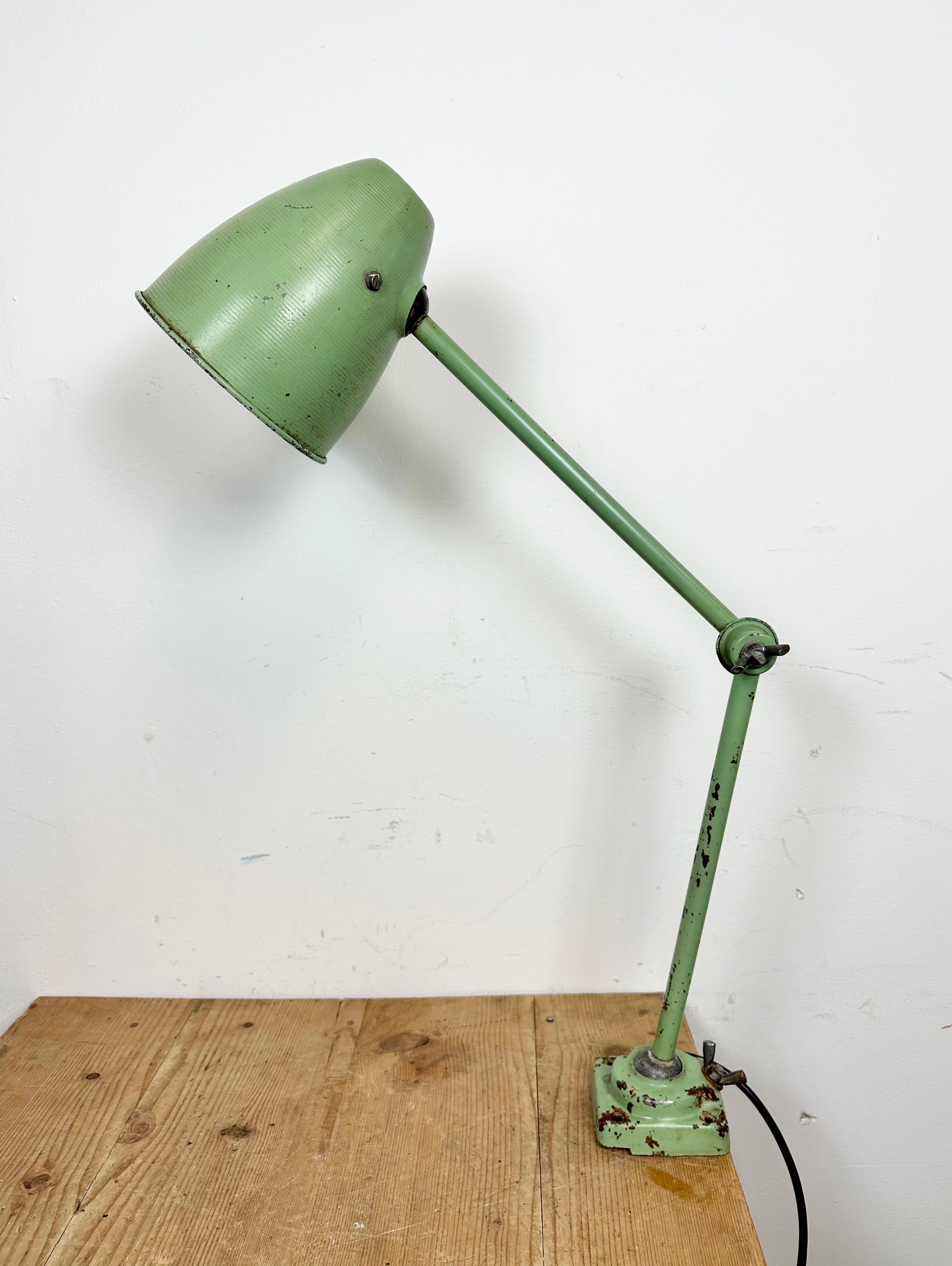 This green industrial desk lamp was made in former Czechoslovakia during the 1960s. It features an iron body with three adjustable joints. The porcelain socket reqiures E 27/ E26 light bulbs. New wire. The switch is situated directly on the shade.