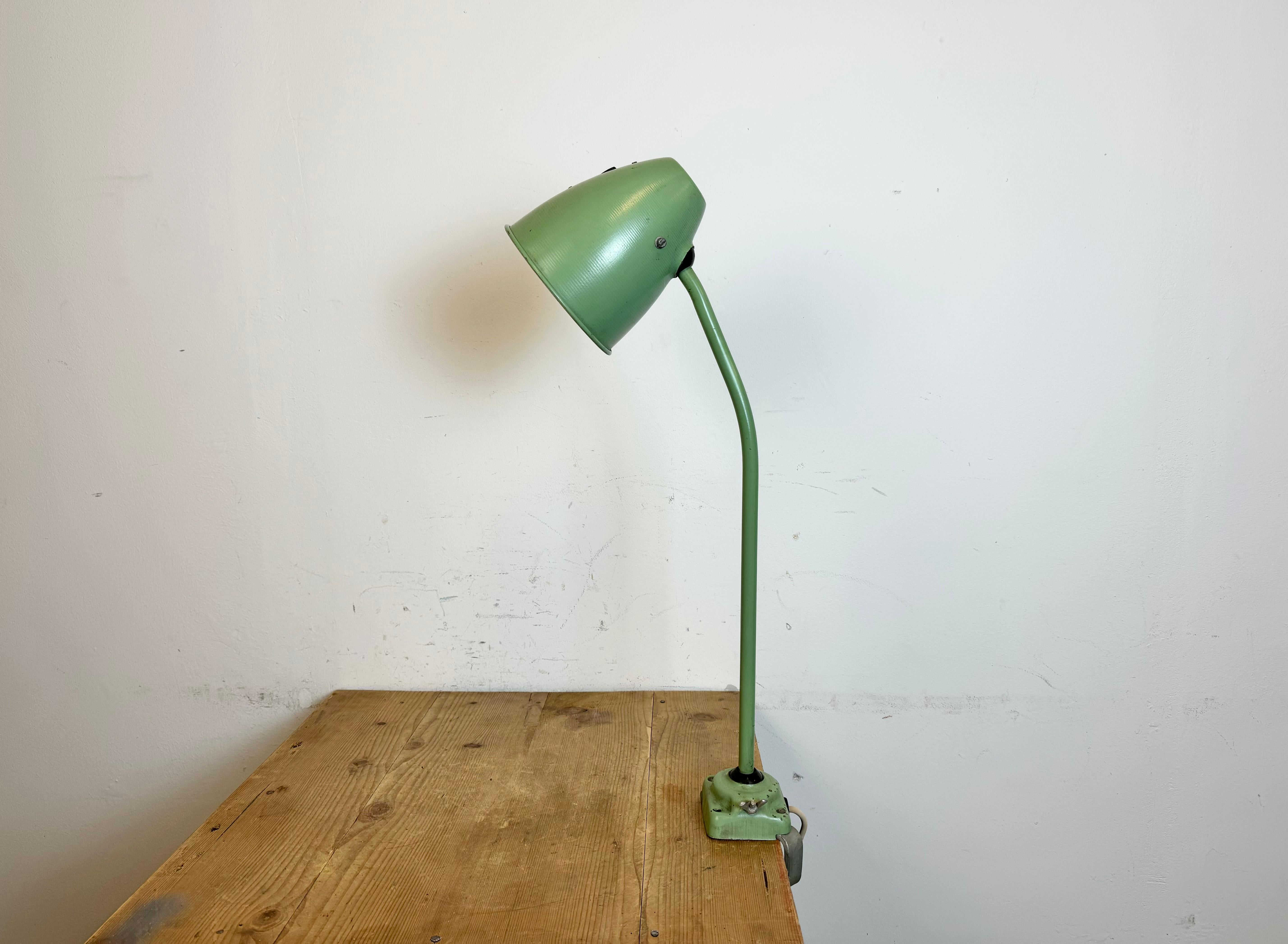 Green industrial adjustable workshop  table lamp was made in former Czechoslovakia during the 1960s. It features an iron shade ,base with clamp and arm with two adjustable joints. The porcelain socket requires standard E 27/ E26 light bulbs.  The