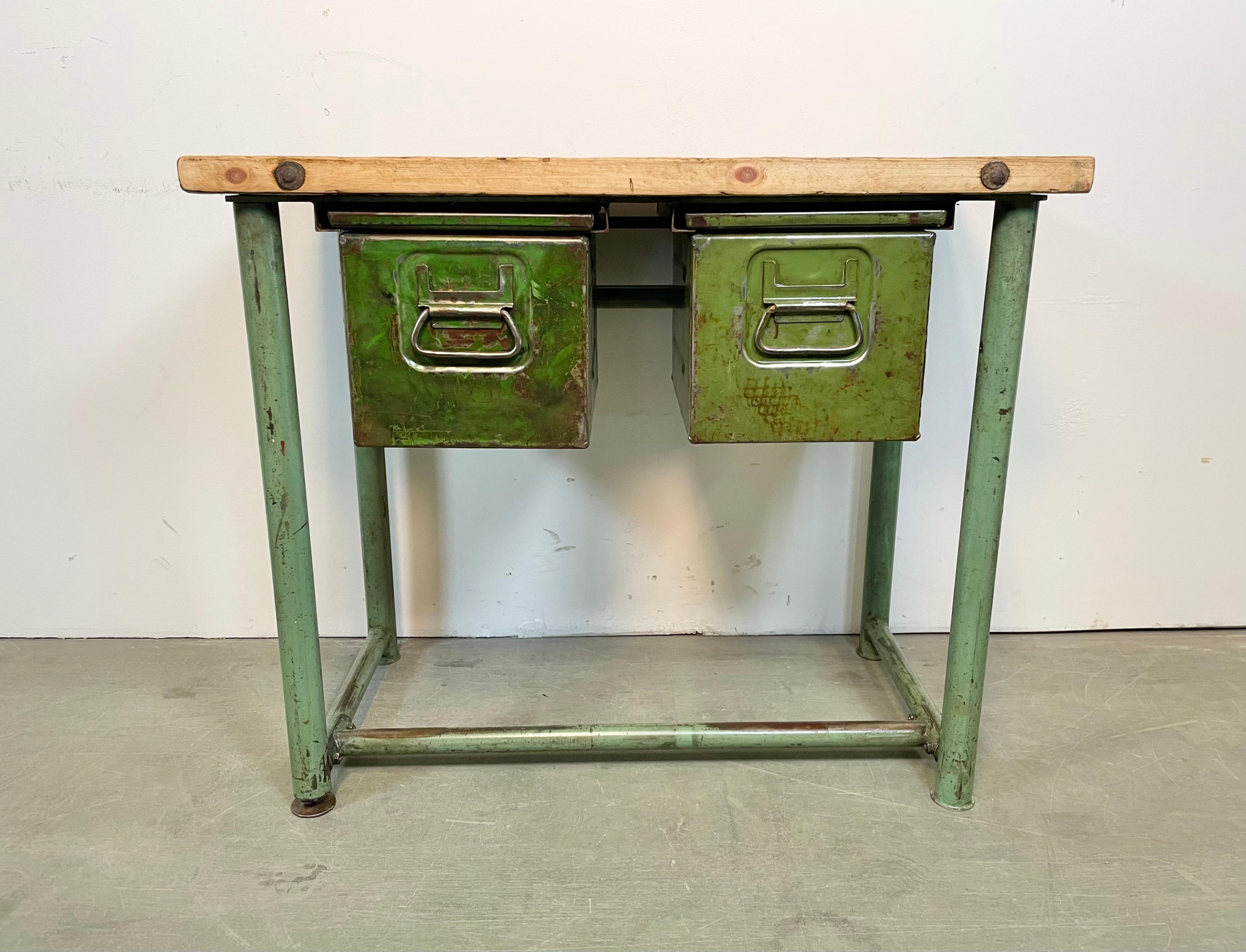 Vintage industrial worktable from the 1960s. It features a green iron construction, solid wooden plate and two iron drawers. Weight: 40 kg.