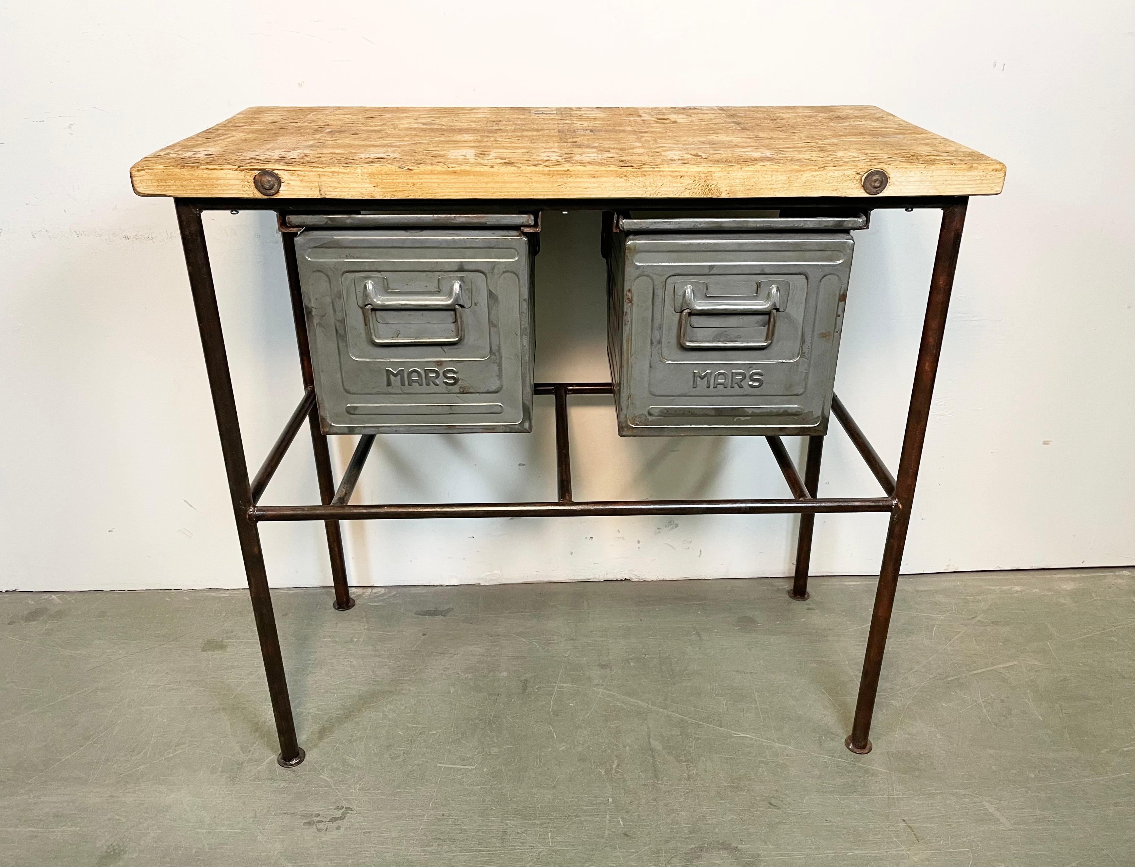 Vintage industrial worktable from the 1960s. It features a red- brown iron construction, solid wooden plate and two grey iron drawers. Weight: 33 kg.