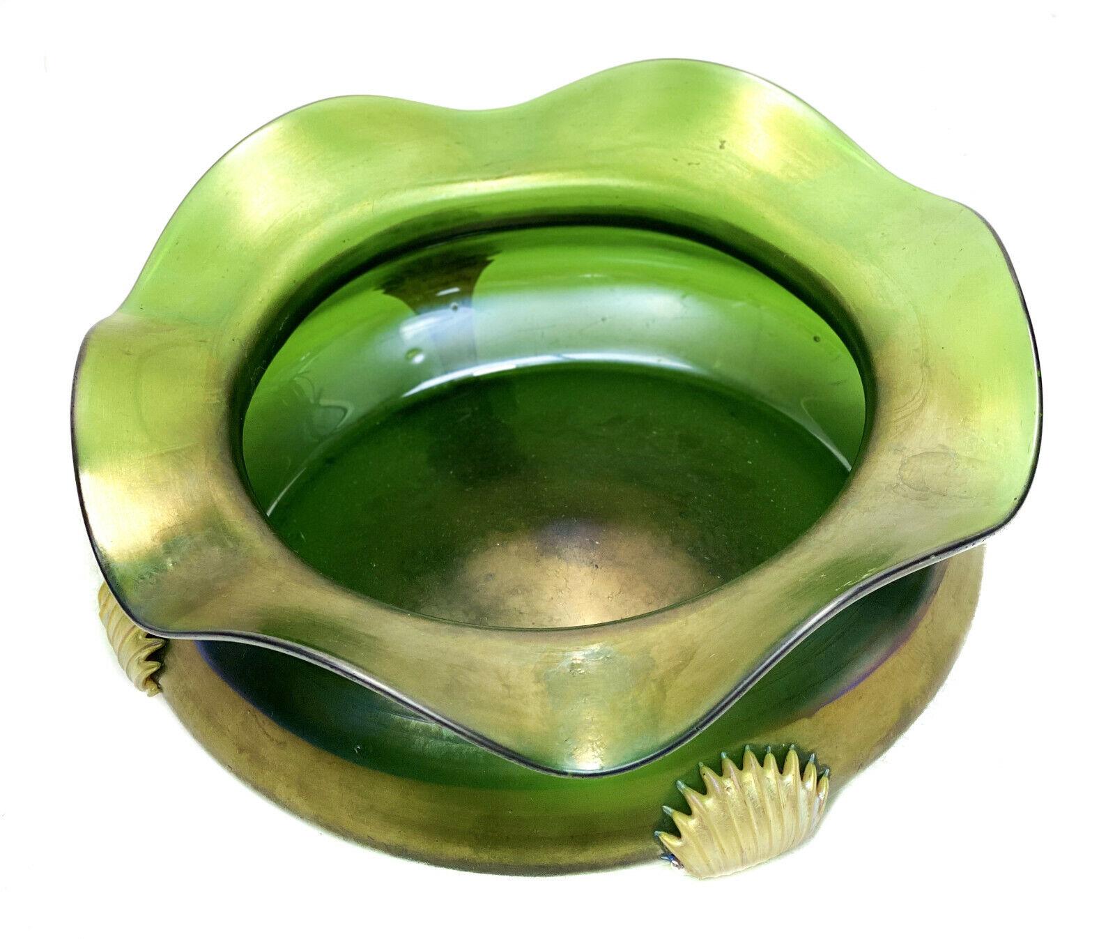 Green Iridescent Art glass bowl w Applied Tendrils, early 20th century

Applied gold fleck tendrils with pointed ends to the exterior of the bowl. Rippled rim to the bowl. Polished pontil to the underside base. Unmarked, the tendrils reminiscent