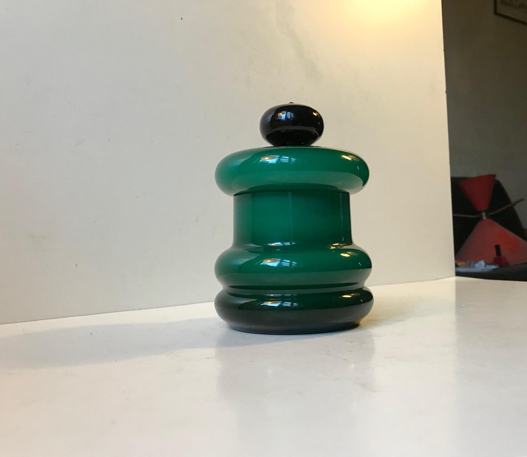 Hooped in shape this emerald-colored lidded jar or trinket was manufactured and designed at Empoli in Italy during the late 1950s or early 1960s. It is composed of a cased outer glass that varies in tone according to the curves of its shape. It's