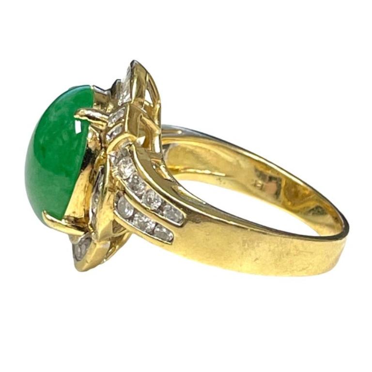 18kt yellow gold rich color green jade statement ring featuring a magnificent oval shaped cabochon green jade in the very center measuring approximately 13.00mm x 10.50mm and is surrounded by a unique halo with ribbons of baguette-cut diamonds