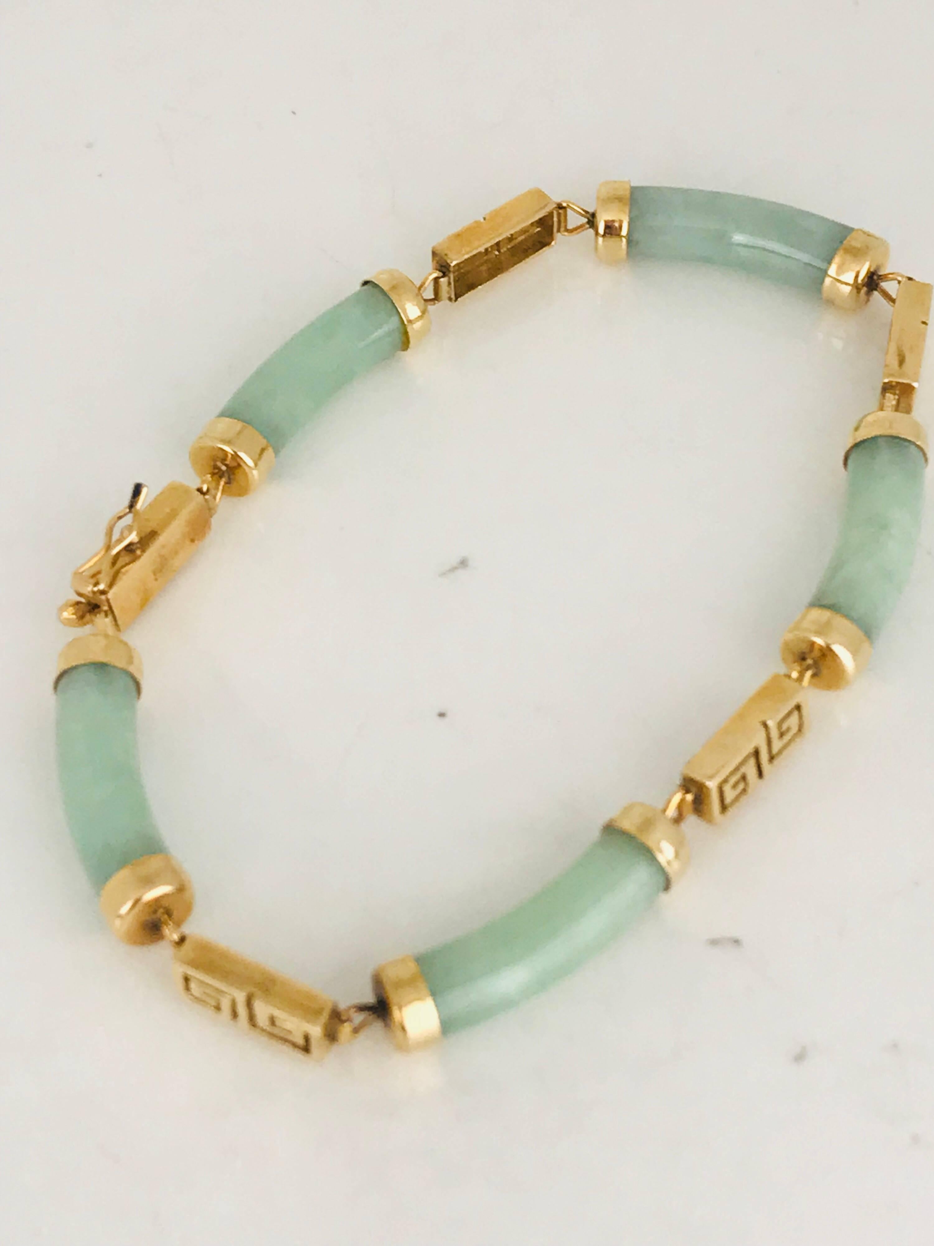 Green Jade, Greek Key Symbol, 14 karat yellow Gold Link Bracelet features polished, curved, cylindrical light green jade links with gold end caps, alternating with rectangular, Greek key-style links.  

Box clasp has a safety clip.

Bracelet