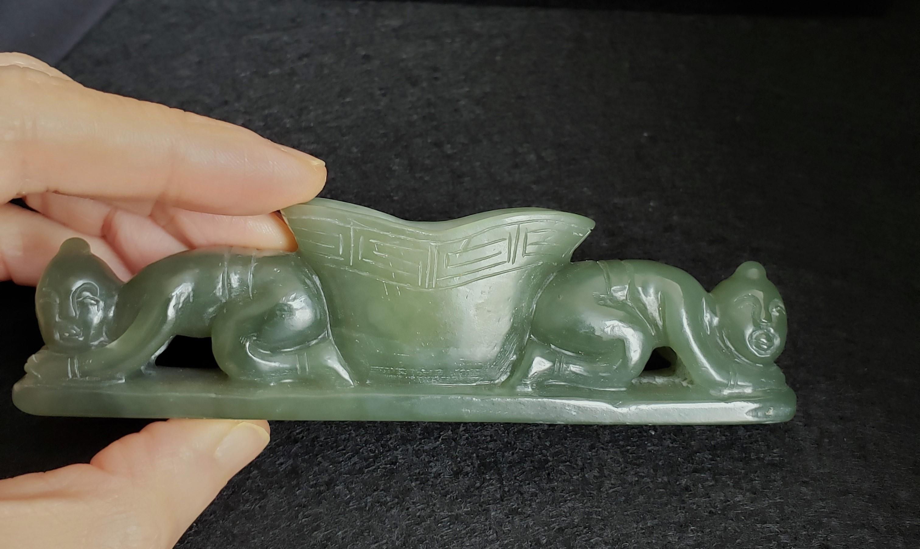 This 19th Century green jade paperweight with a water dropper, 碧玉元宝水盂镇纸, features a yuanbao 元宝 shaped water dropper at the center, with rectangular spiral 回纹 patterns decorating the edges above the yuanbao 元宝. 

Two servants are kneeling on the