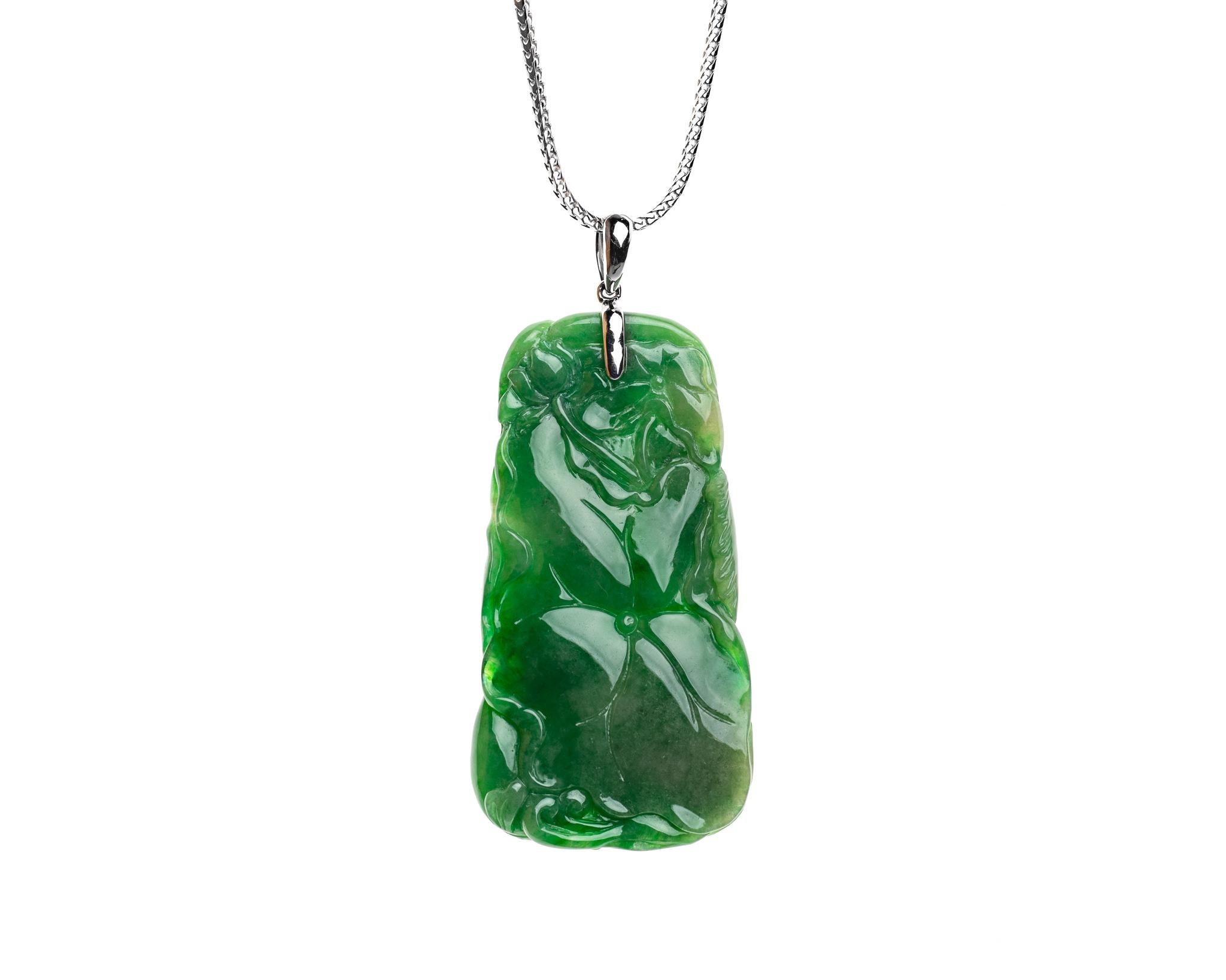 This all natural green jadeite jade carved fish and lotus leaf set on an 18k white gold bail with one small brilliant round diamond.  
Both sides of pendant can be worn. One side showcases two fishes swimming around the lotus leaf which symbolizes