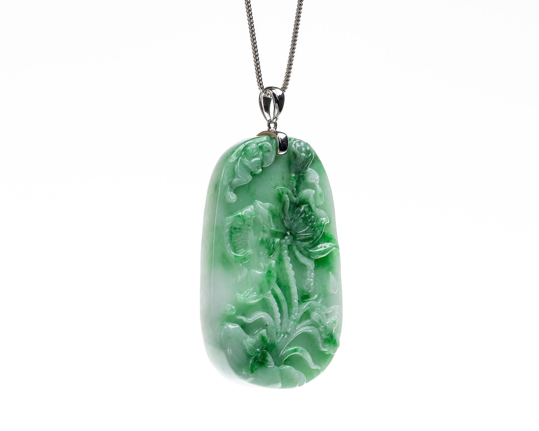 This is an all natural, untreated jadeite jade carved lotus flower with fish pendant set on an 18K white gold bail.  The carved lotus flower with fish symbolizes harmony, wealth and prosperity. 
  
It measures 1.43 inches (36.4mm) x 2.09 inches