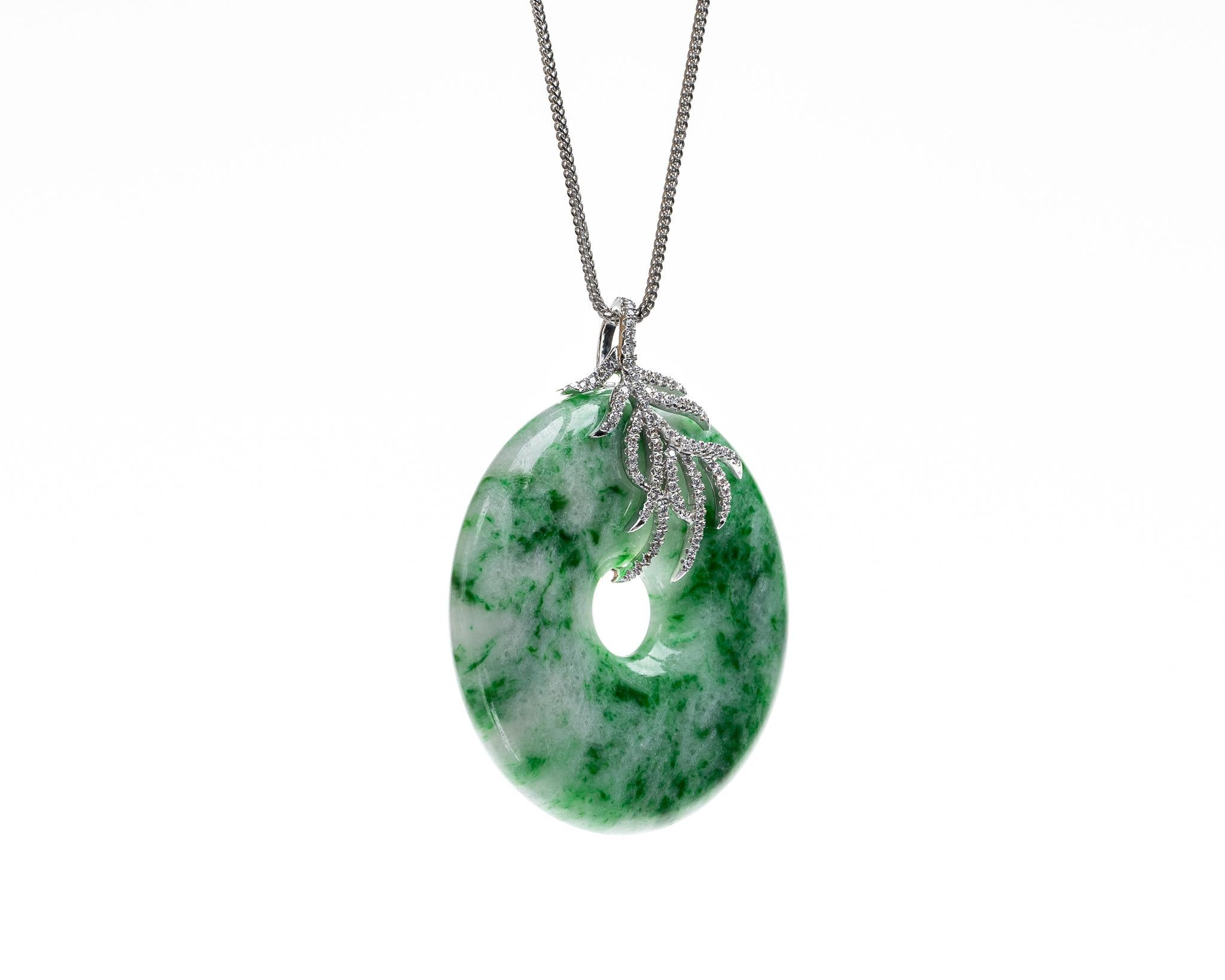 This is an all natural, untreated jadeite jade carved pi disc and diamond pendant set on an 18K white gold and diamond bail.  The carved pi disc symbolizes peace.   

It measures 1.57 inches (39.9mm) x 1.89 inches (48.1mm) with thickness of 0.25