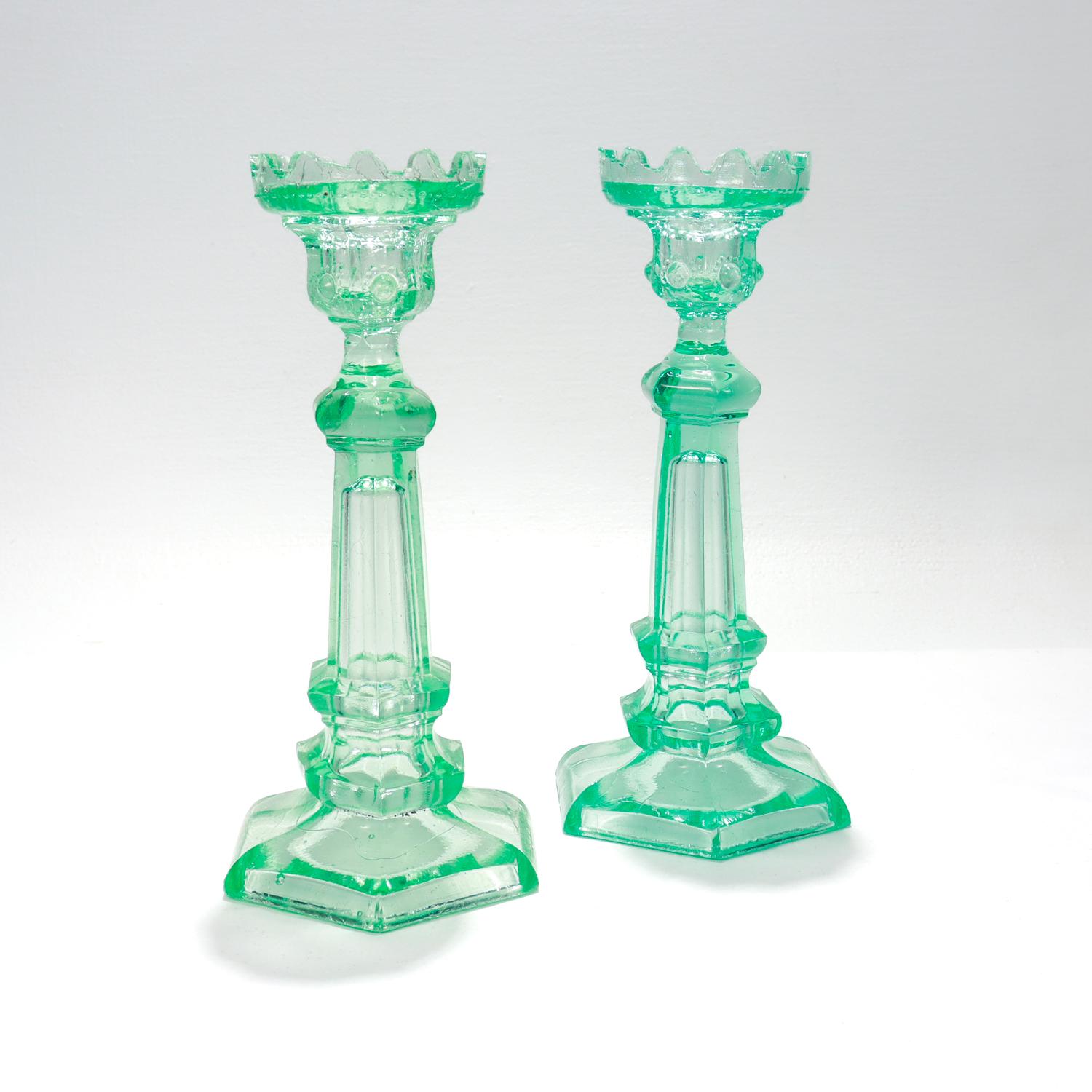 Un buen par de candelabros antiguos de vidrio prensado.

Por el fabricante de vidrio danés Kastrup (predecesor de Holmegaard) 

En vidrio de uranio verde, que presenta fluorescencia bajo los rayos UV. 

Con tapas festoneadas sobre una bobeche