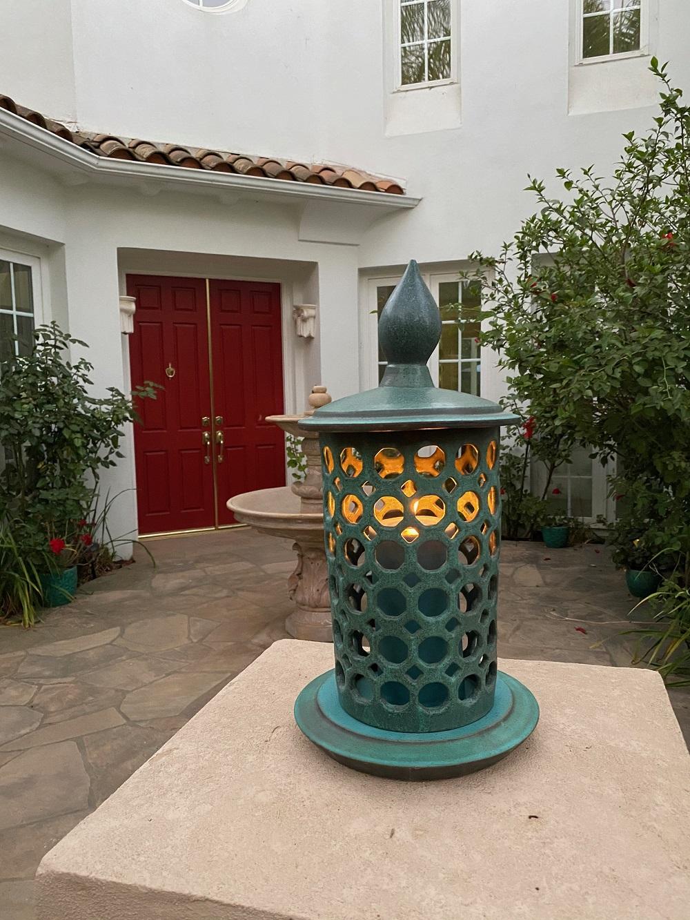 A new twist on a traditional lantern this three-piece design, is wheel thrown and hand pierced stoneware with a weathered bronze glaze. Small holes are created when the clay is still wet and then each hole is painstakingly enlarged and smoothed when