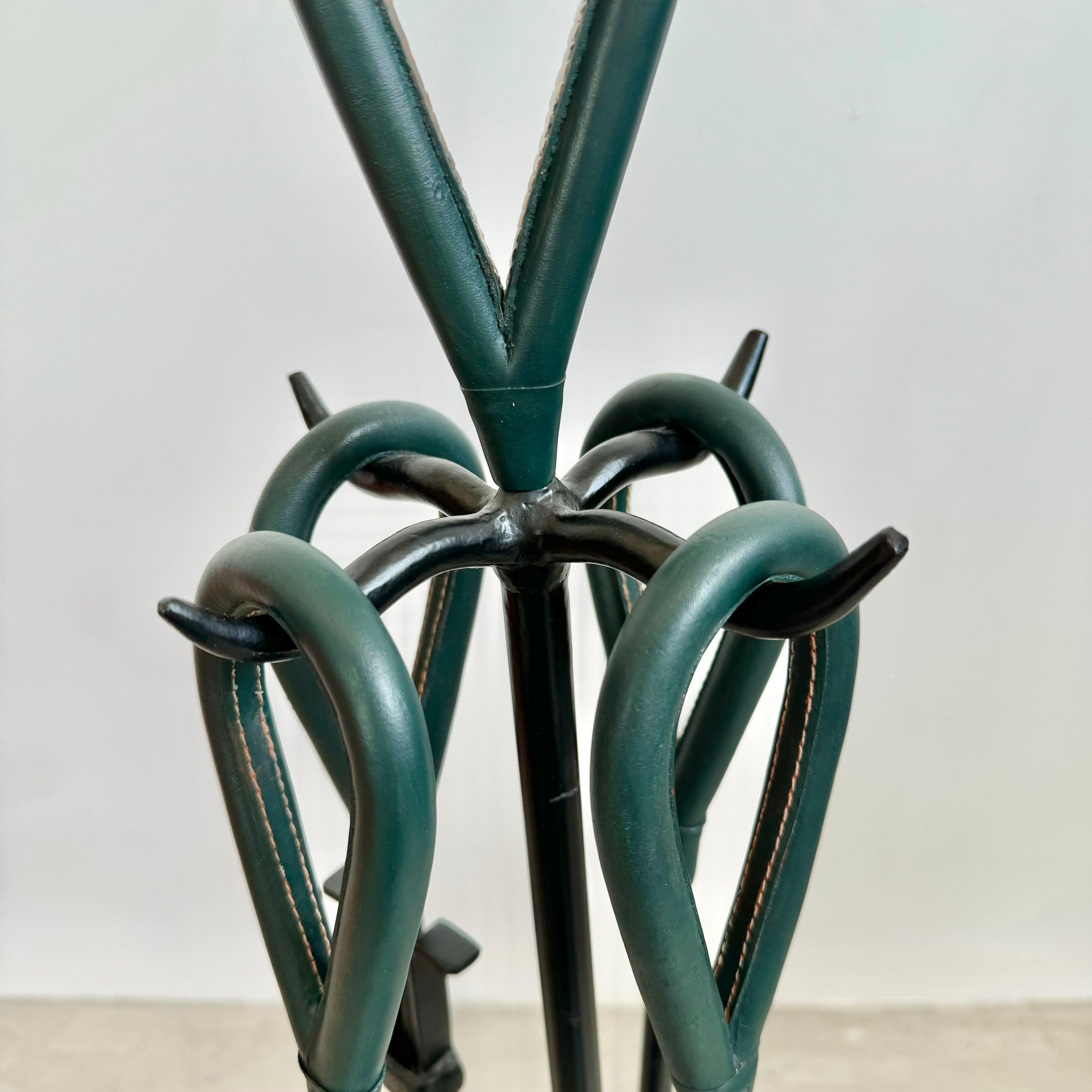 Beautiful fireplace set in the style of Jacques Adnet. Black iron frame with wooden handles wrapped in dark green leather with signature Adnet style saddle stitching. Fireplace set includes stand, along with four tools: broom, dustpan, tongs and