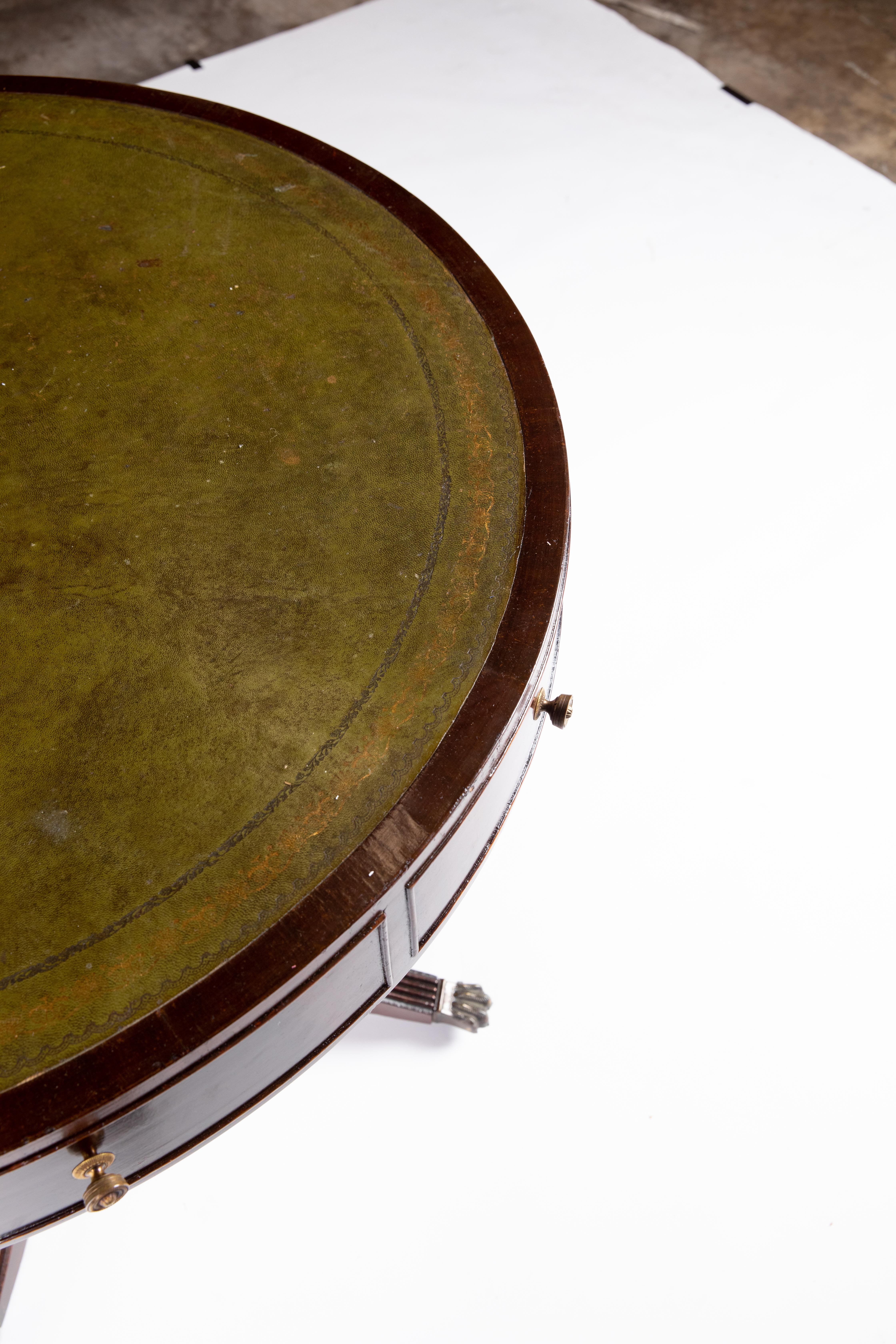 British green leather top drum table - brass capped claw feet on casters.