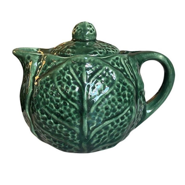 A small mid-century majolica teapot with a green cabbage leaf motif. This beautiful piece will be a great addition to a tea set. The body is round and features textured cabbage leaves all around. It has a small spout and handle. The lid is round and