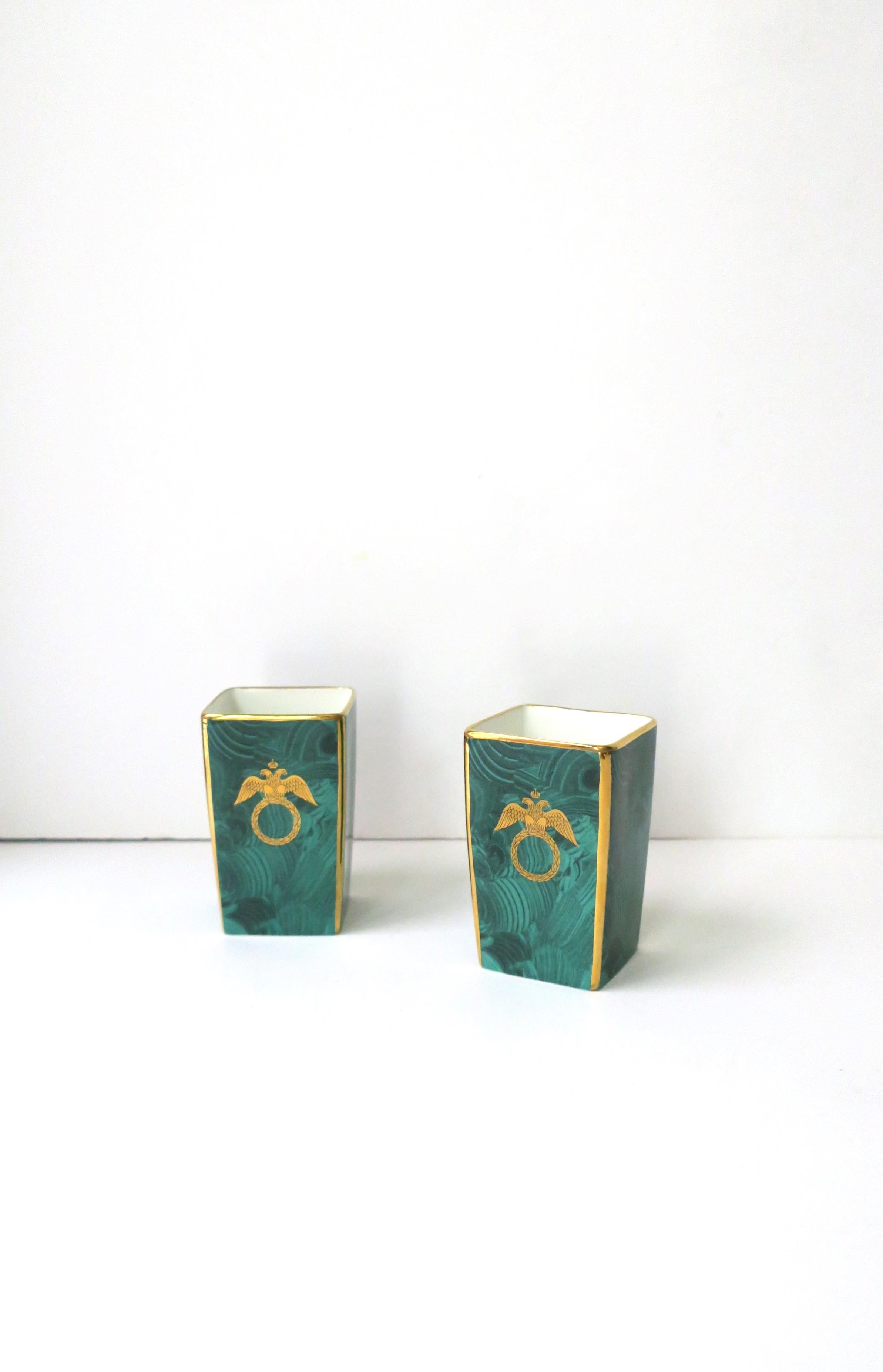 A pair of English green malachite porcelain desk pen holders or vanity vases, in the Federal style, circa late-20th century, England. Pair are porcelain with a green malachite-style exterior, a gold wreath and eagle bird with crown design in gold